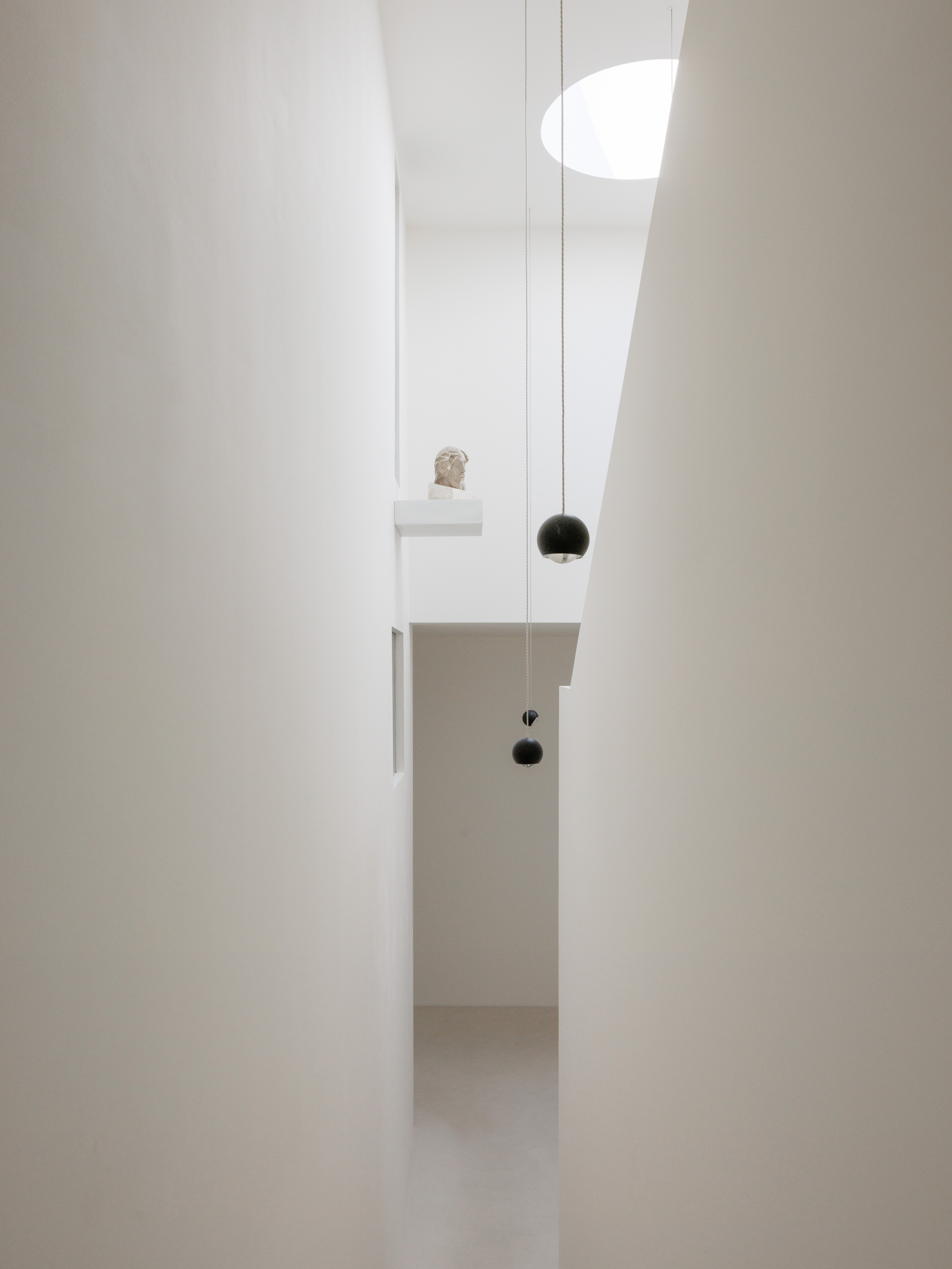 Narrow view through doorway showing pendant lights and a small sculpture on a shelf niche