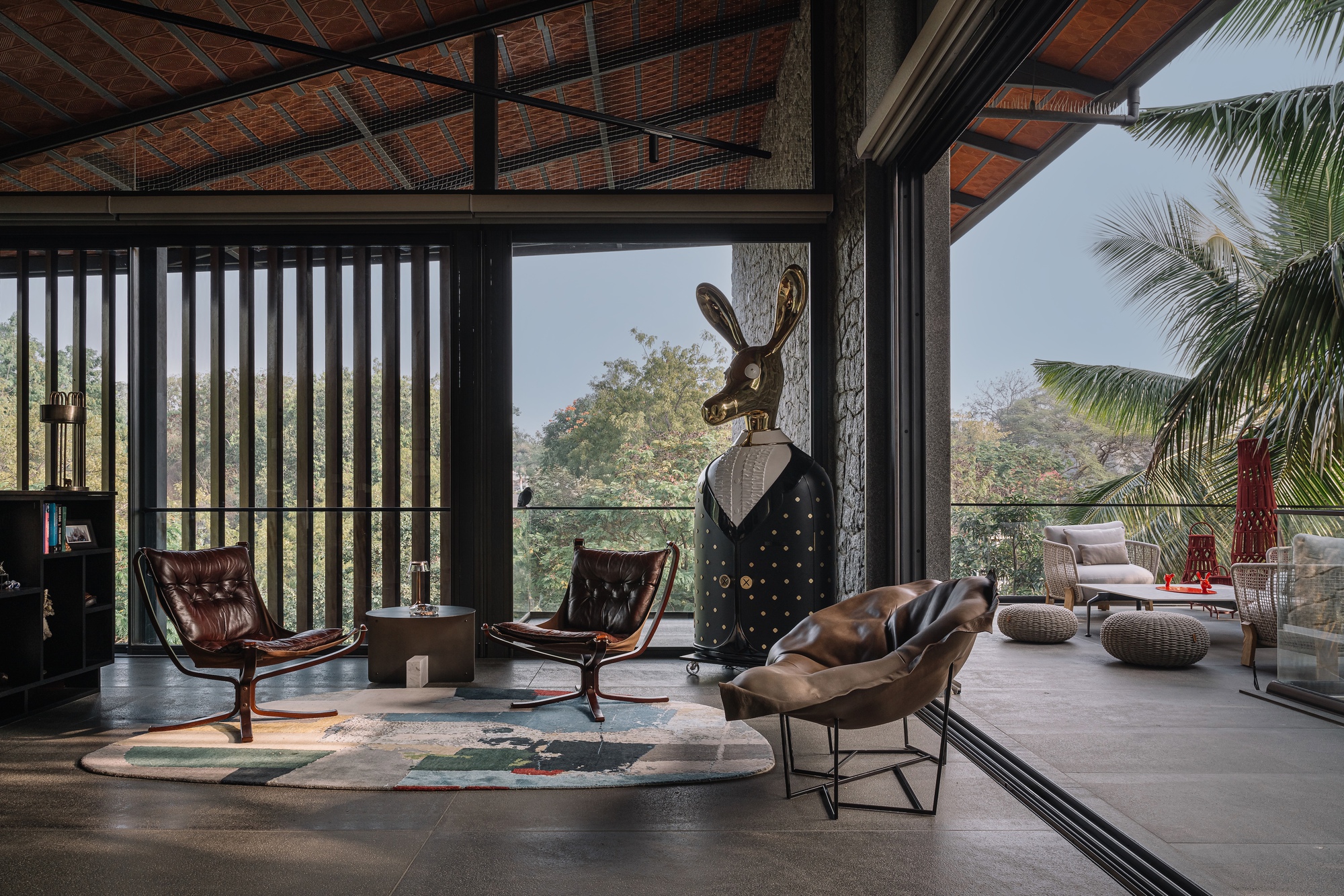 Living area with exposed brick vault ceiling, vertical timber screen, and glazed openings to palm trees outside