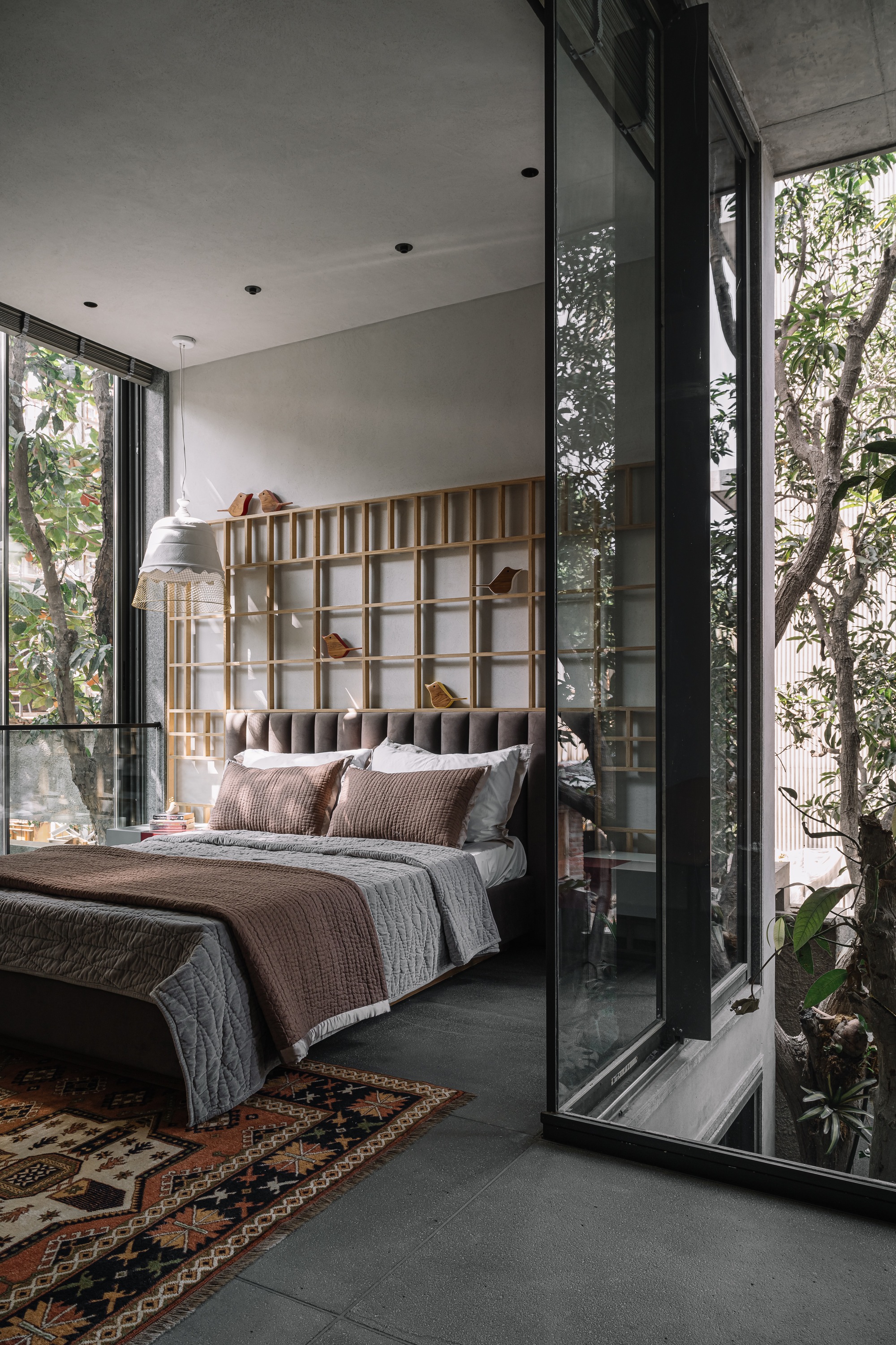 Bedroom with timber grid headboard opening to planted courtyard through floor-to-ceiling glazing