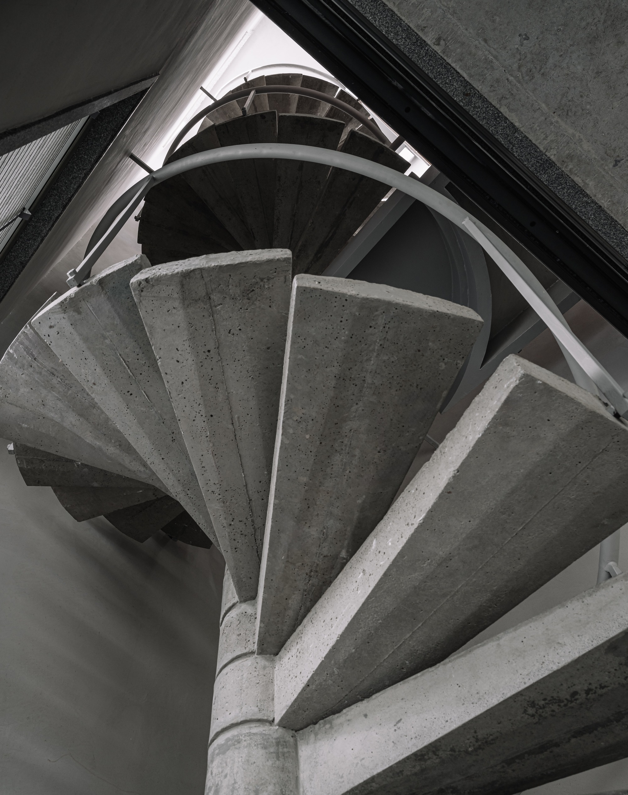 Top-down view of spiraling concrete staircase with metal handrail wrapping around central column