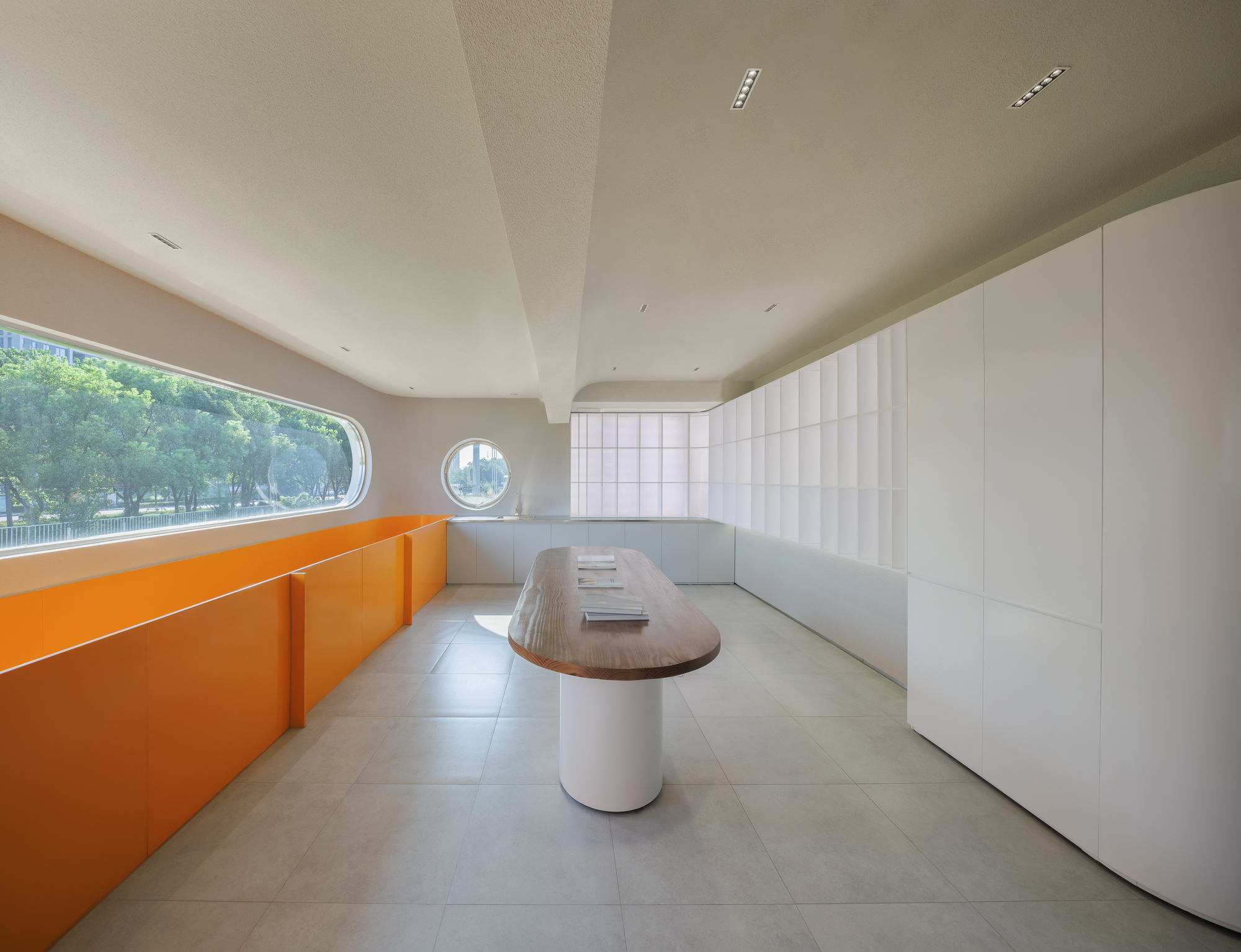 Interior meeting room with orange cabinetry, oval table, circular porthole and curved horizontal window