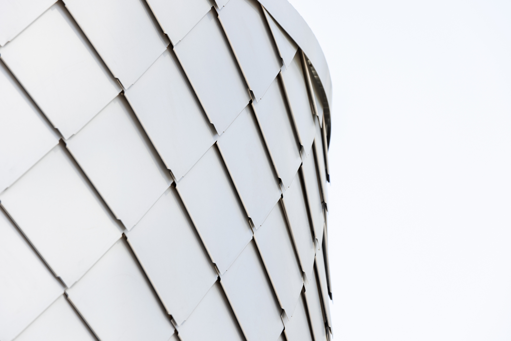 Close-up of white rectangular shingles arranged in a diagonal pattern across a curved surface