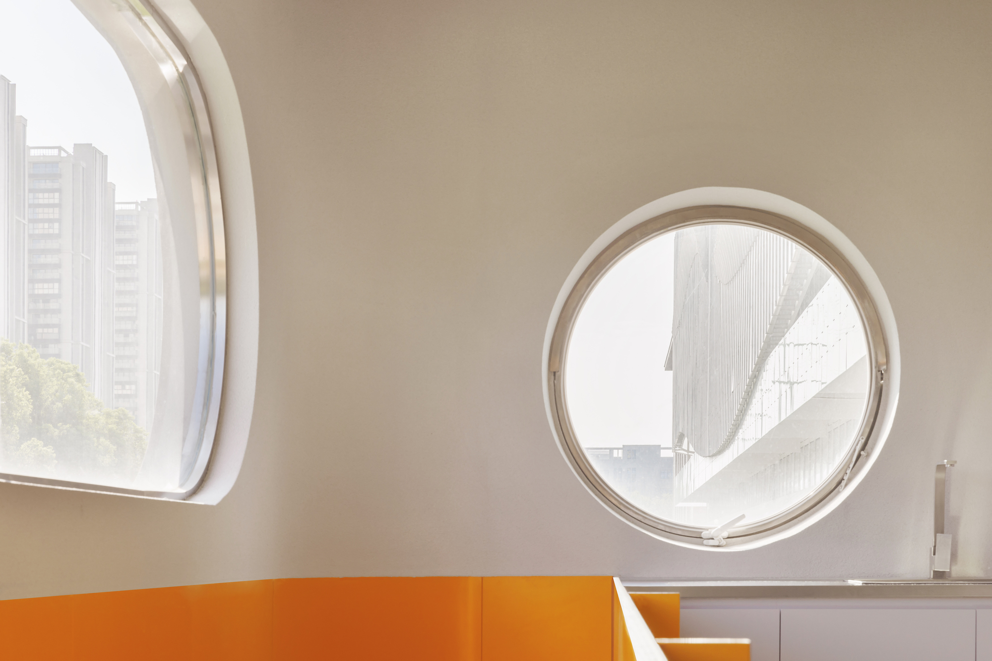 Circular porthole window framing a view of an external bridge structure under overcast sky