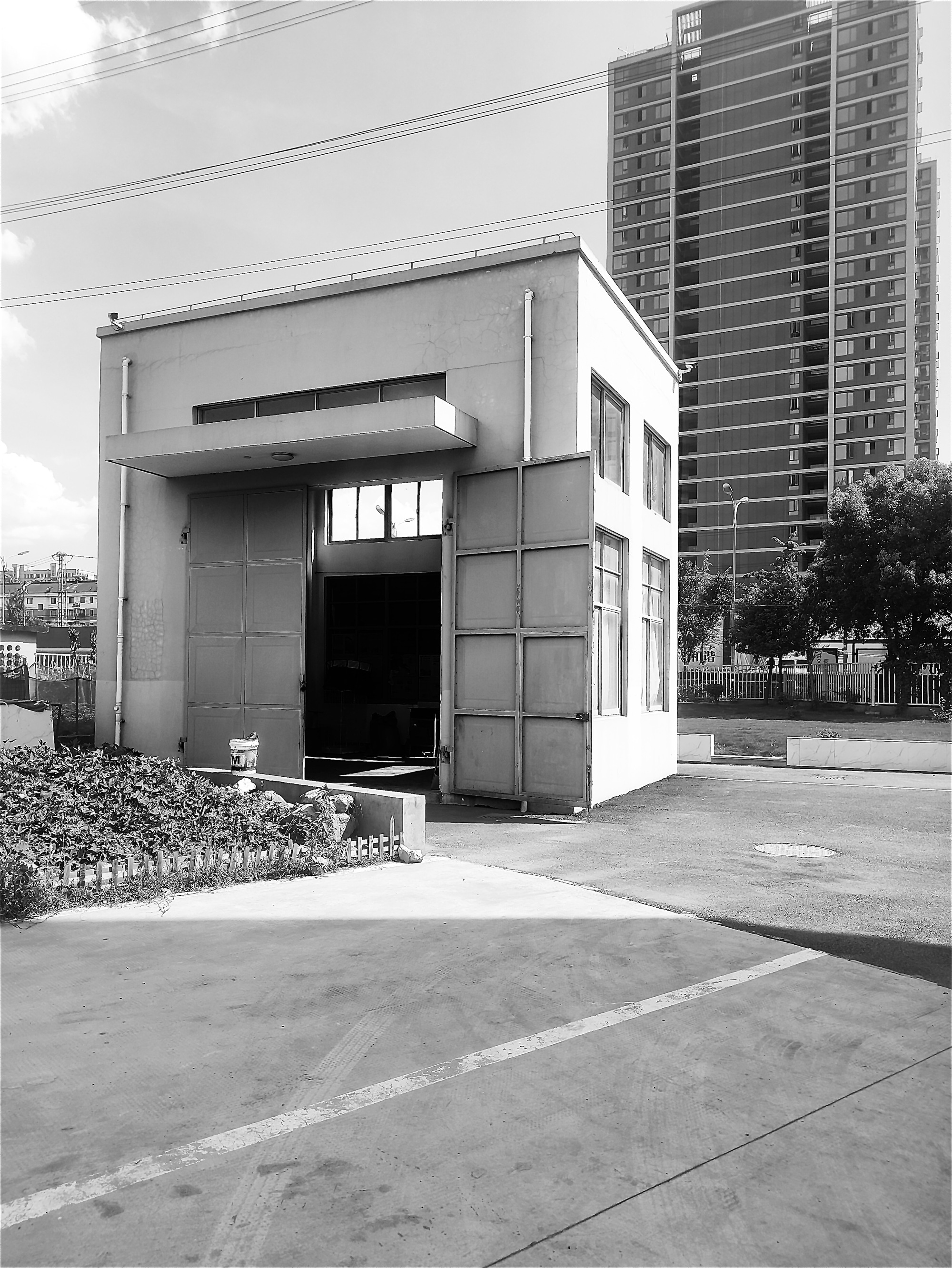 Street view of white stucco facade with cantilevered volume and residential towers behind