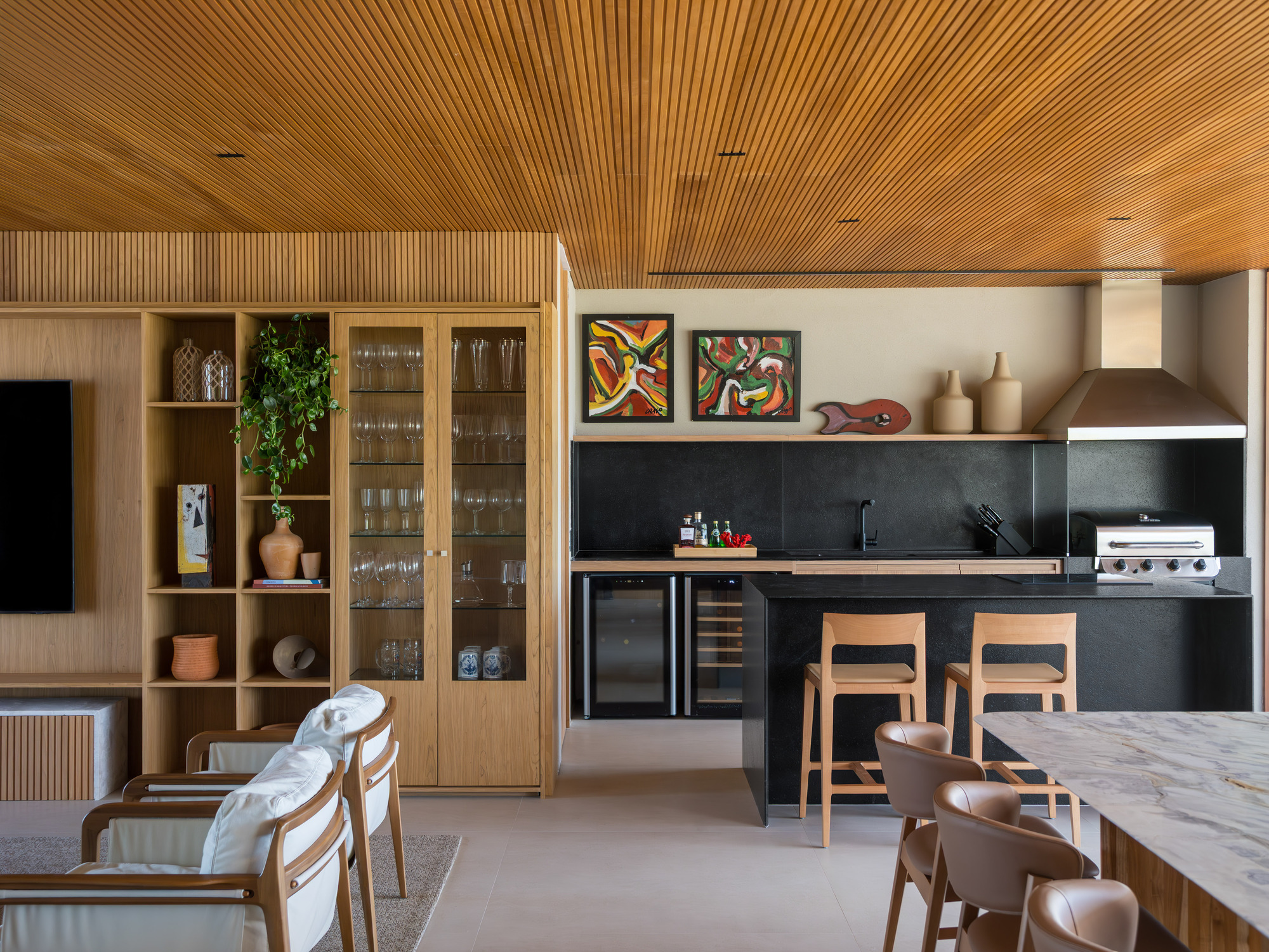 Open kitchen with black stone countertops and timber millwork beneath a continuous slatted wood ceiling