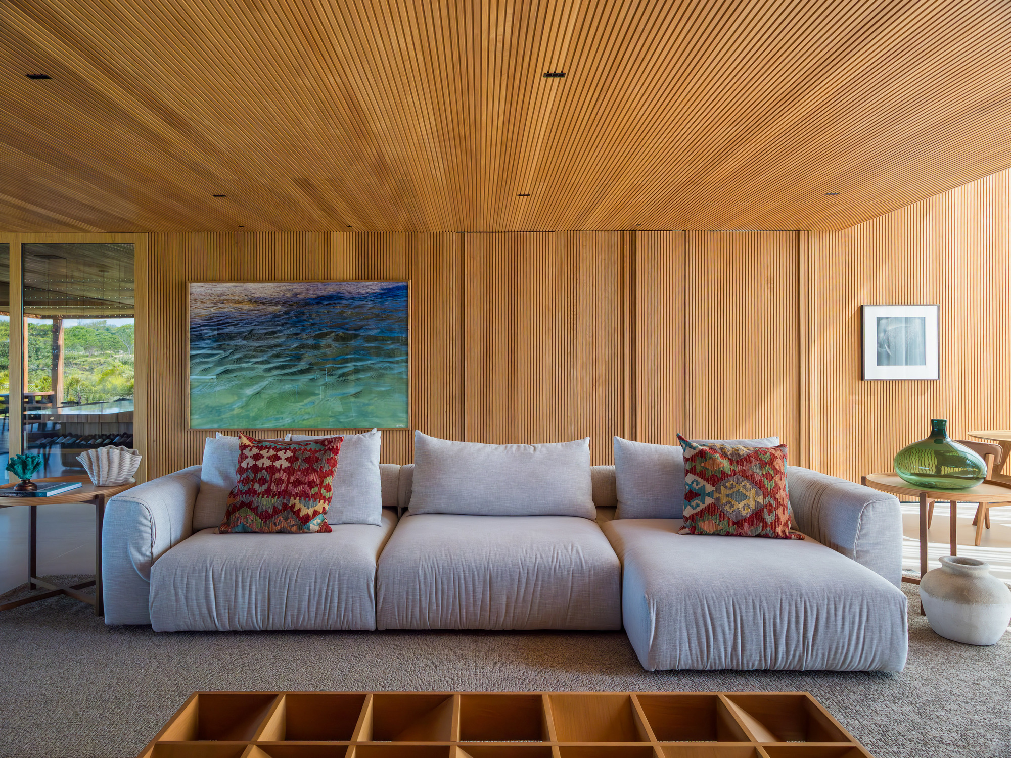 Living room with vertical timber slat walls and slatted ceiling beneath recessed downlights