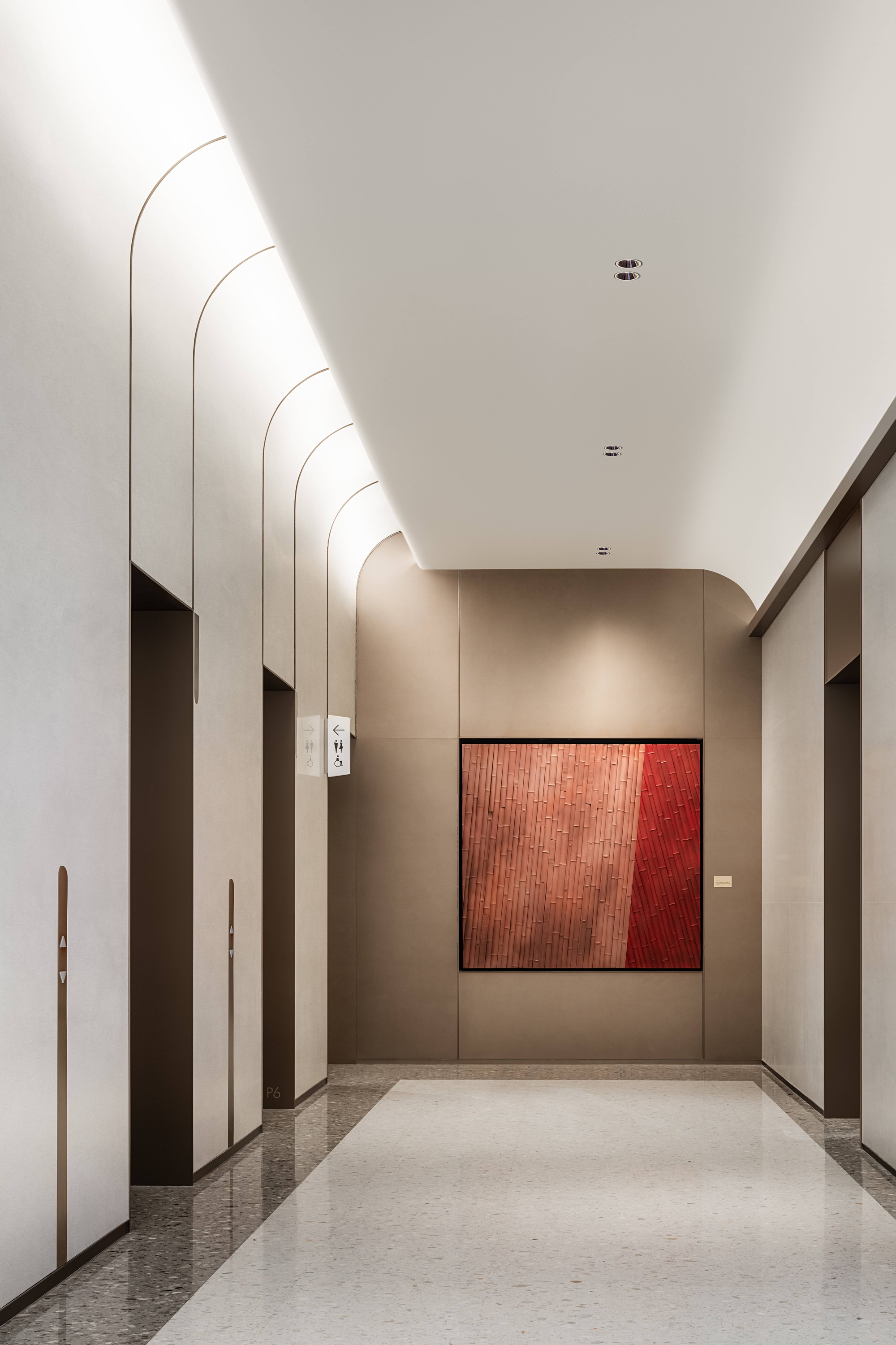 Elevator lobby with arched ceiling reveals and a red textural artwork on taupe paneled wall