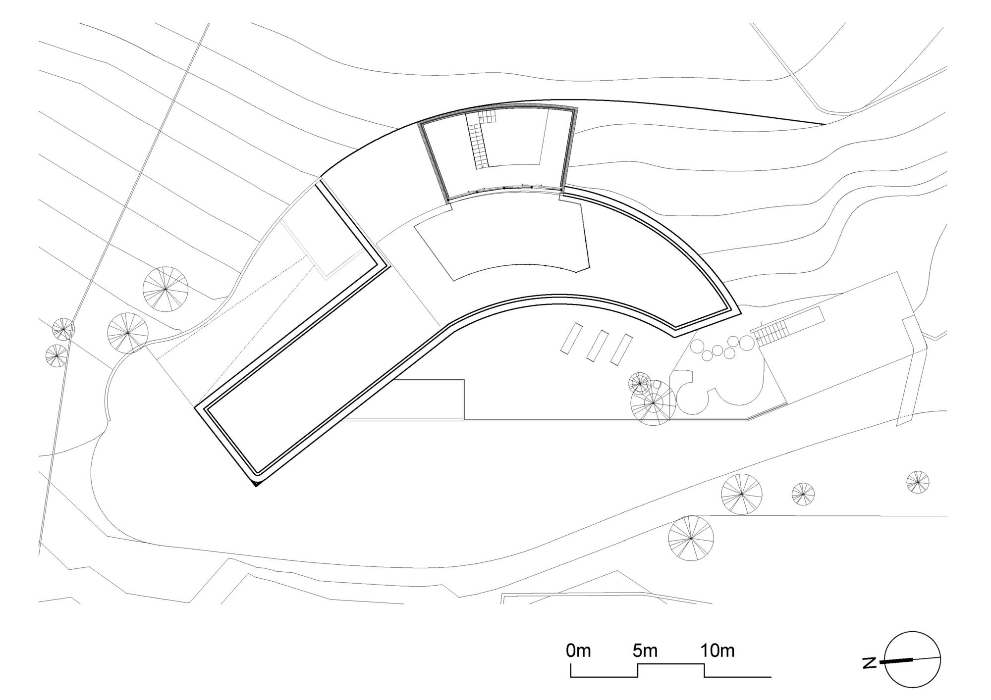 Roof plan drawing of the bent, curving building outline set among site contour lines, trees and a driveway loop