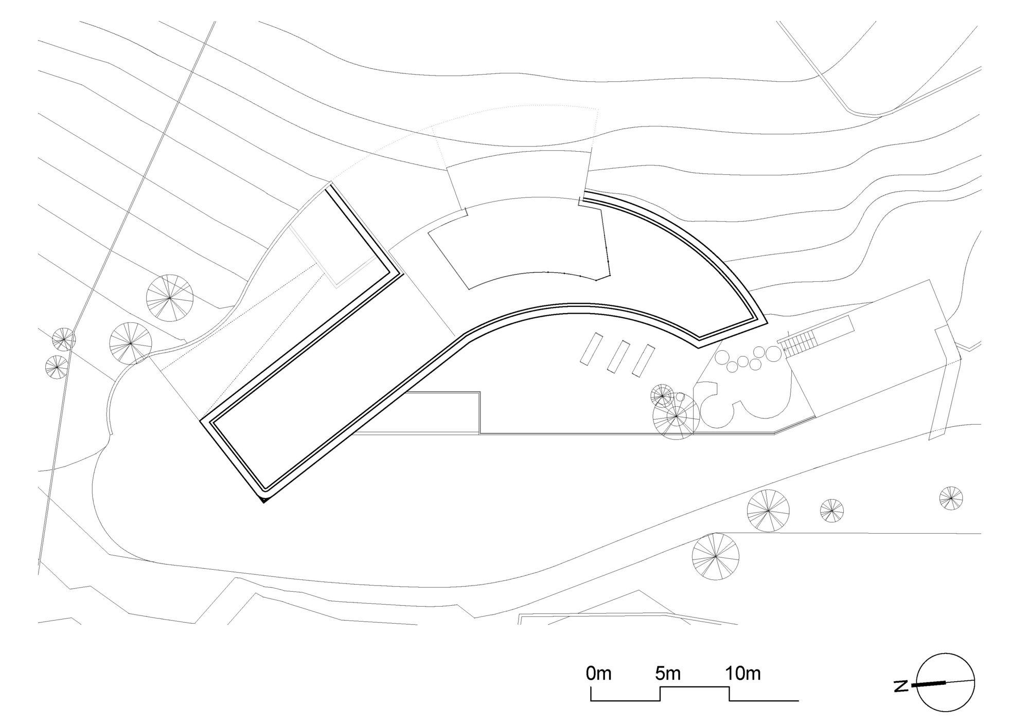 Site plan drawing showing the curved building footprint, terrain contours, scattered trees and access road, with a lighter outline for the upper volume