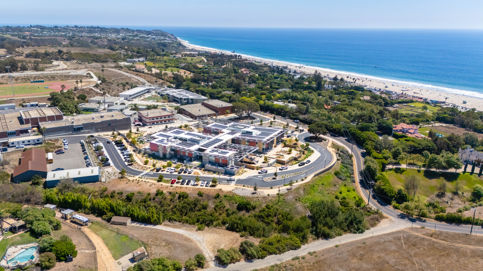 Aerial view of the campus complex nestled between coastal hillside and ocean shoreline