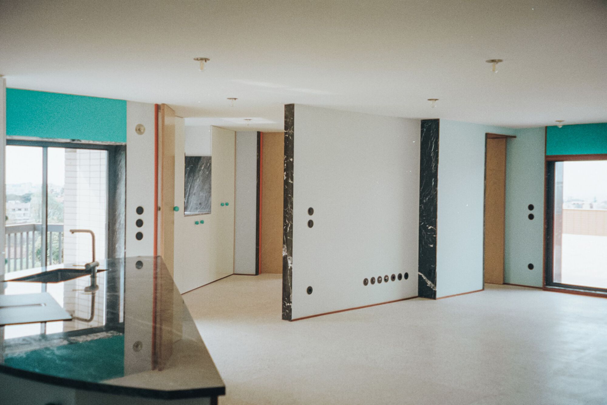 Open-plan interior with marble-clad partitions, pale wood cabinetry, and windows framing the cityscape
