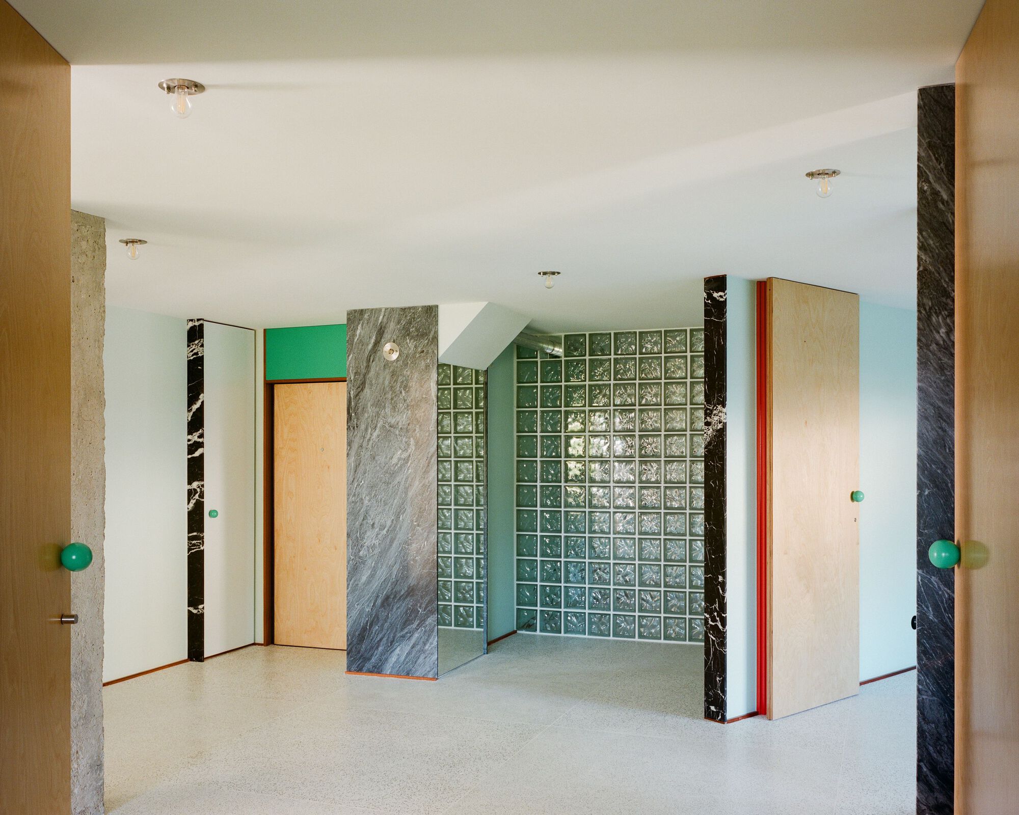 Corner view showing marble wall panels flanking a glass block partition with turquoise backing