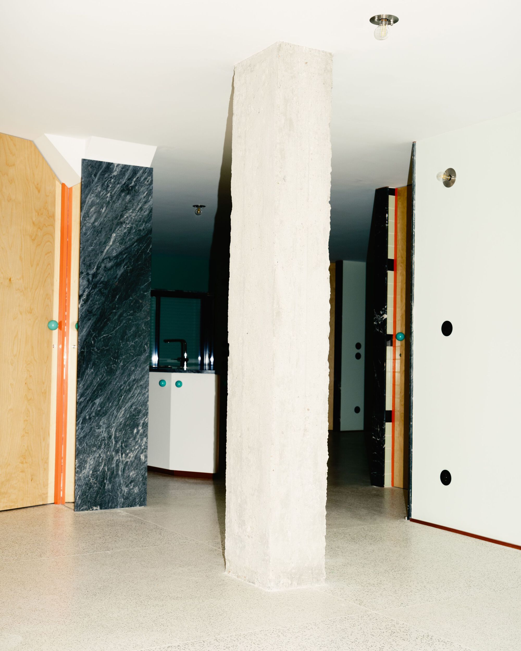 White textured concrete column standing in a hallway lined with marble and pale wood panels