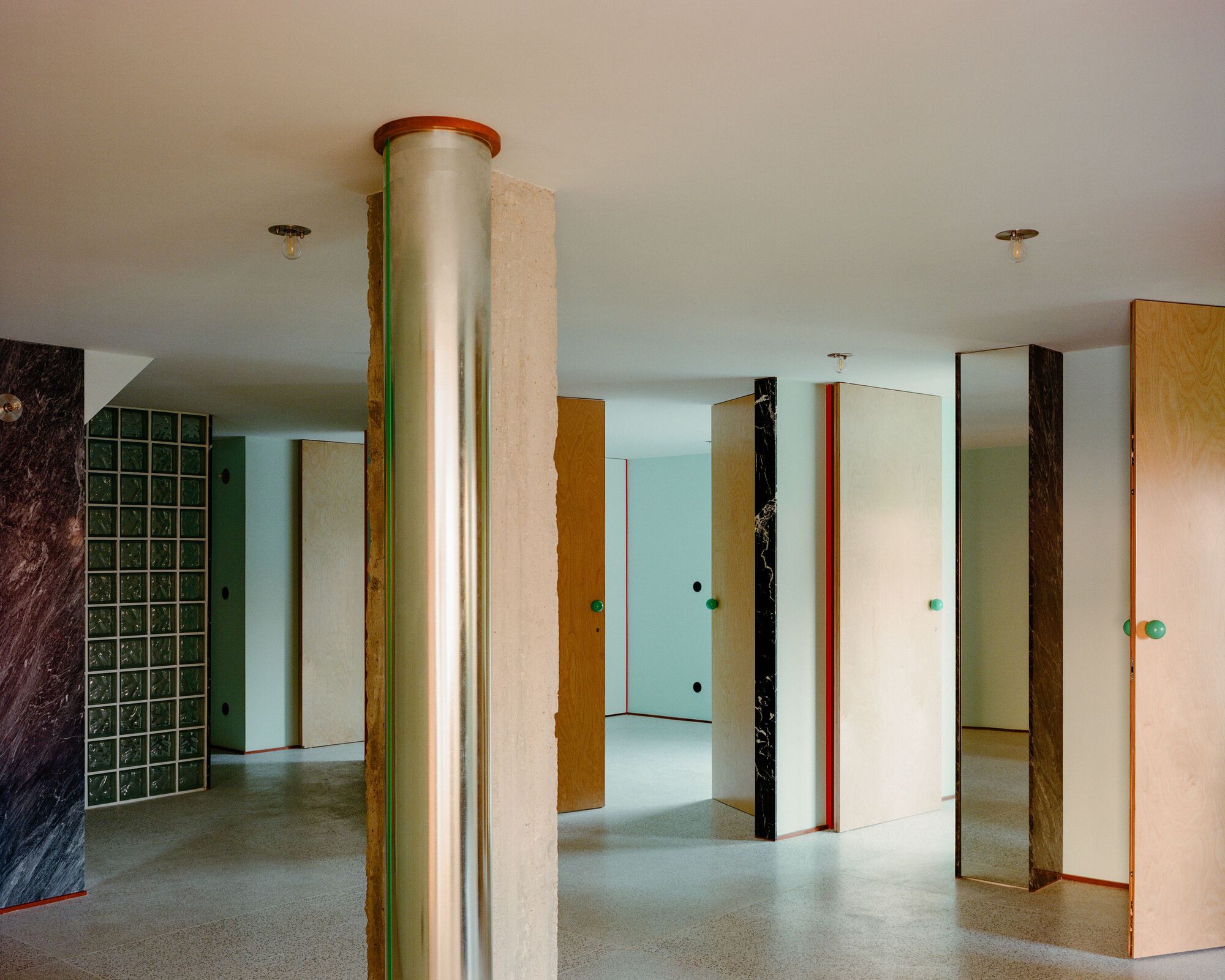 Interior space with cylindrical column wrapped in red trim and freestanding partition panels in varied finishes