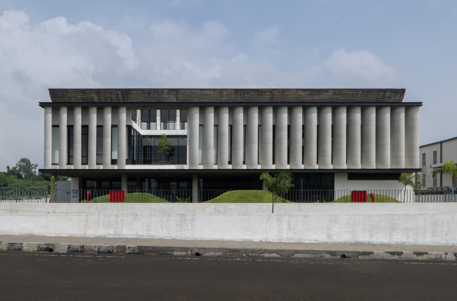 Street view of the precast concrete columnar facade rising above a concrete retaining wall