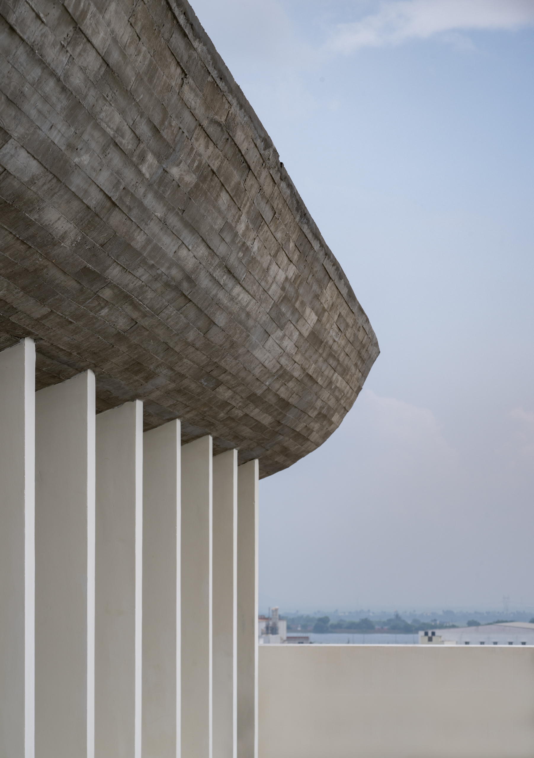 Detail of the board-formed concrete soffit cantilevering above cylindrical white columns