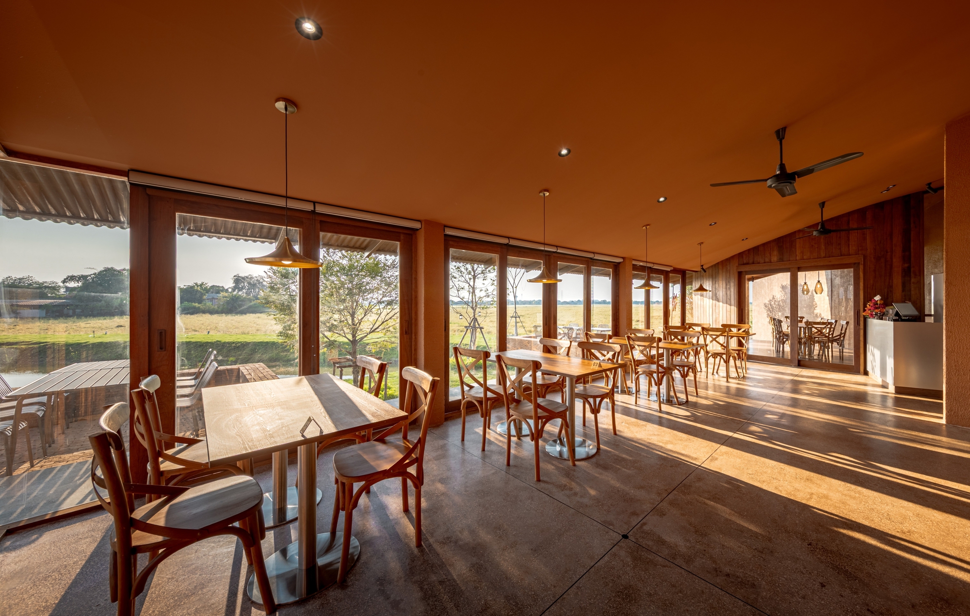 Dining hall with timber-framed glazing and polished concrete floors in afternoon sunlight