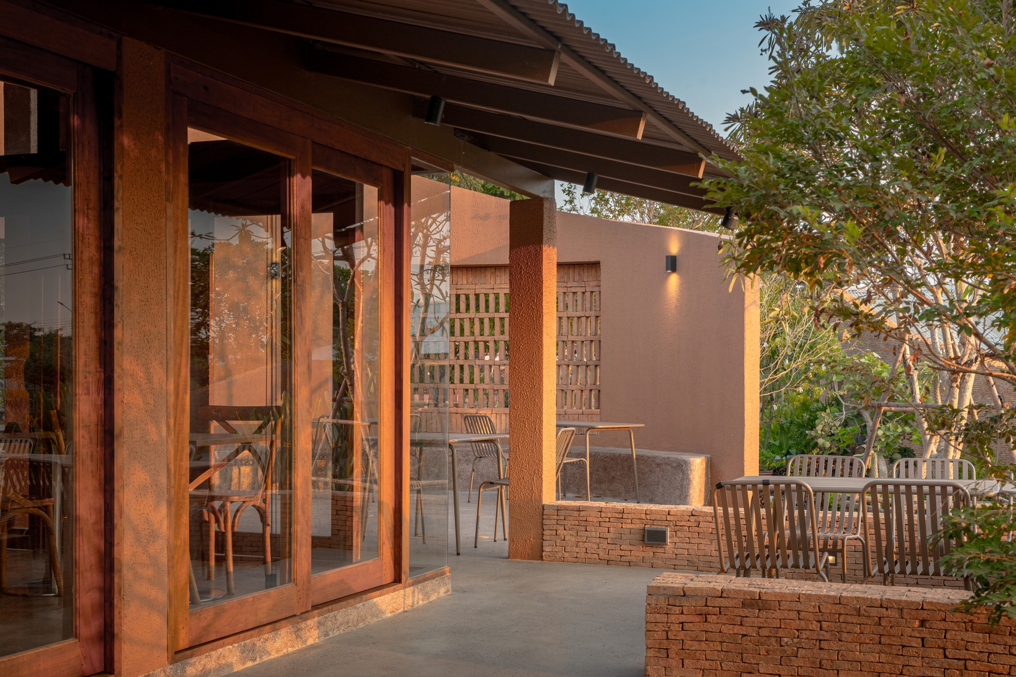 Timber folding doors opening to terrace with brick planter walls and lattice screen at twilight