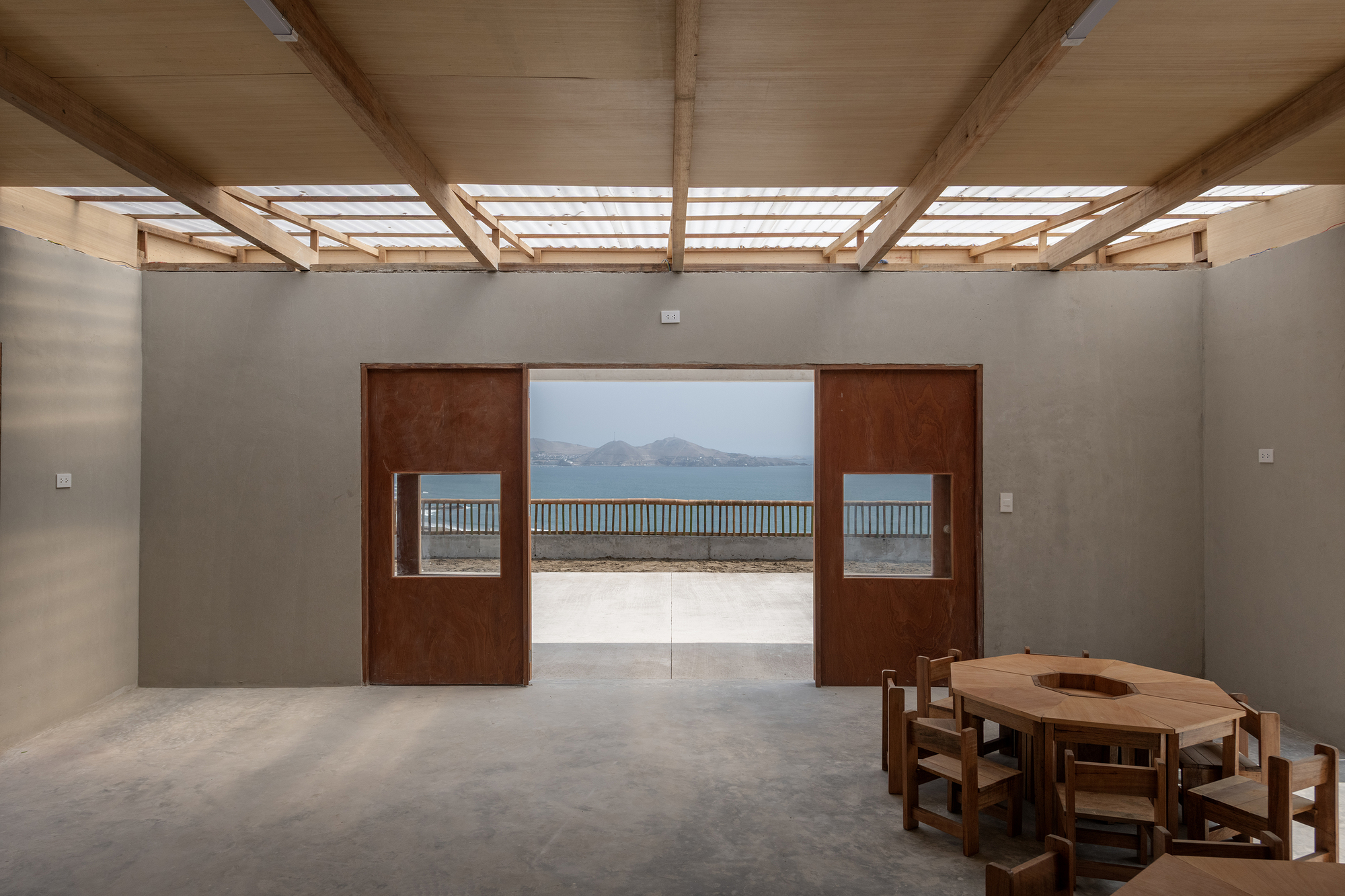 Interior view through sliding timber panels to courtyard terrace with slatted timber roof above