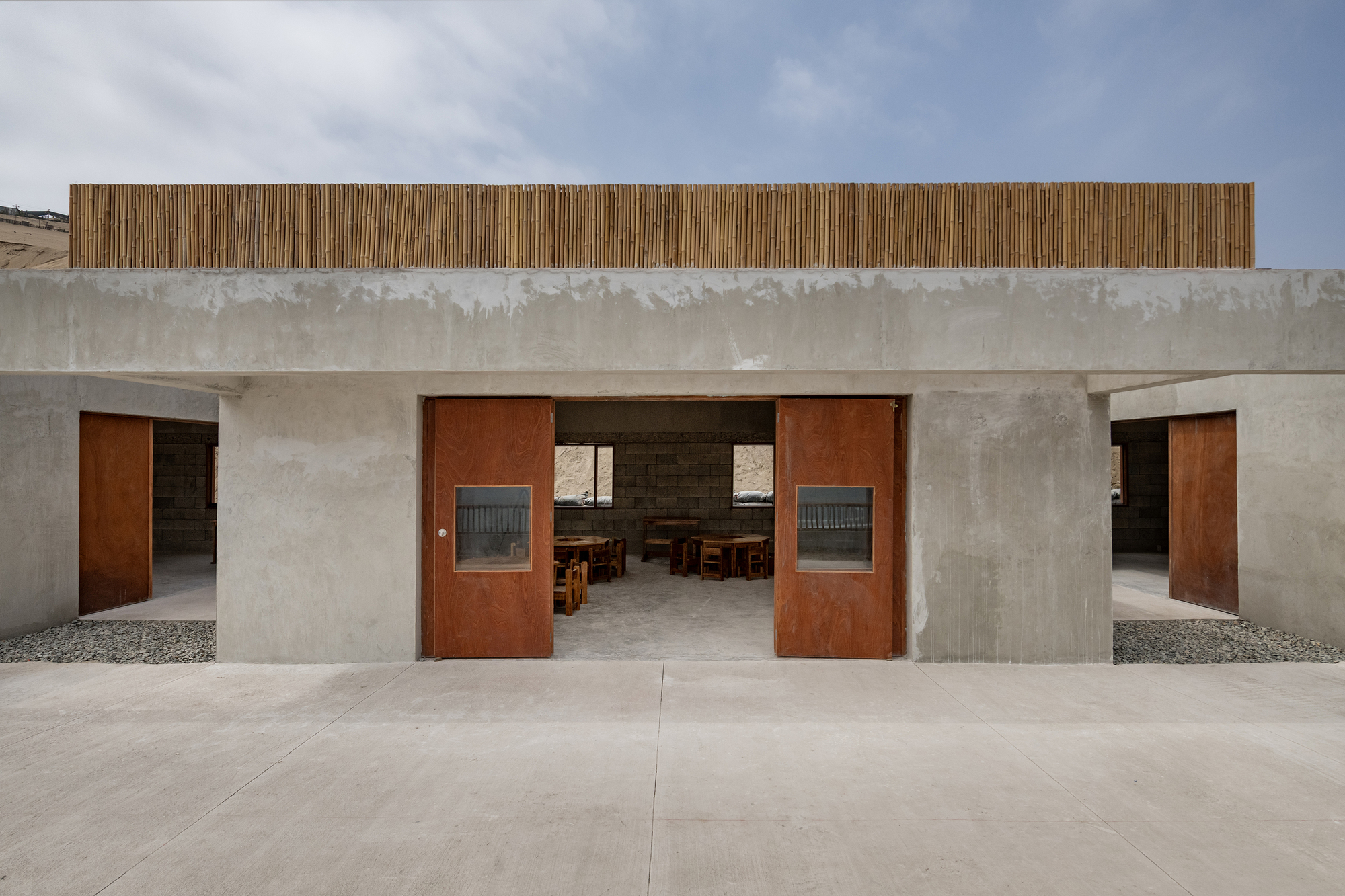 Entry threshold with rusted steel pivot doors flanking a central passageway through concrete walls