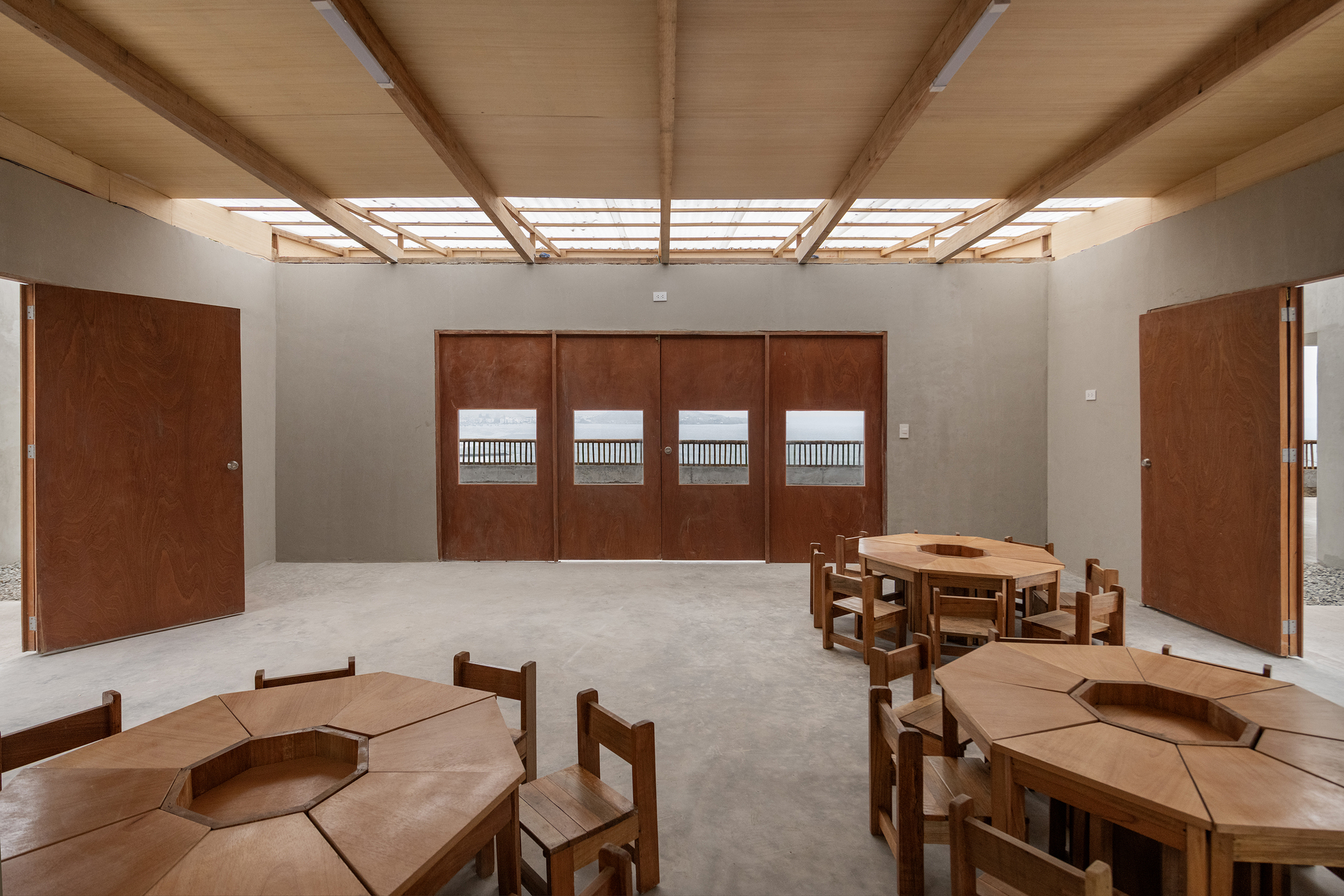 Interior classroom space with timber beam ceiling, skylights, and hexagonal modular furniture