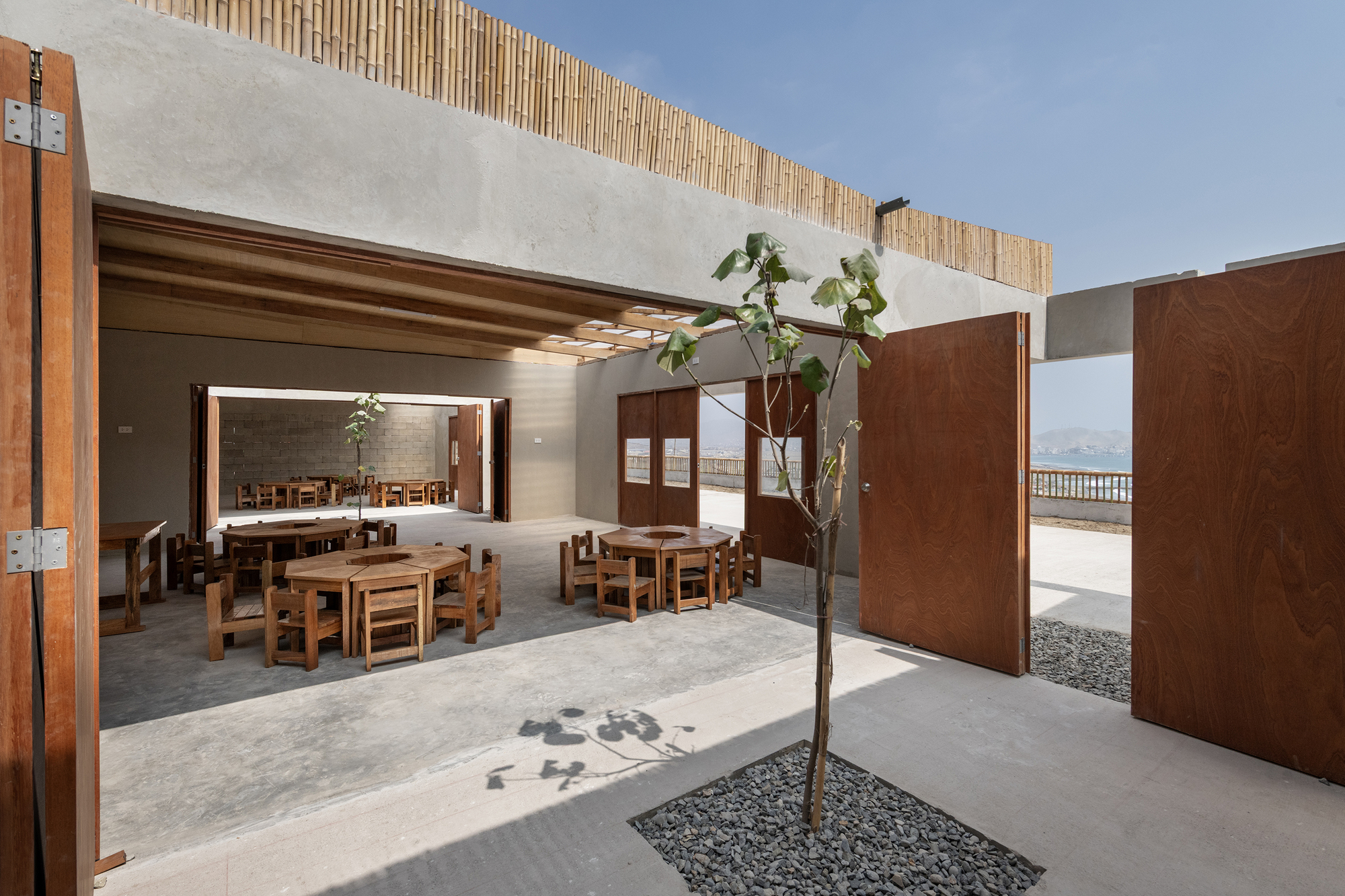 Courtyard with timber screens, concrete flooring, a planted tree, and views through wooden doorways