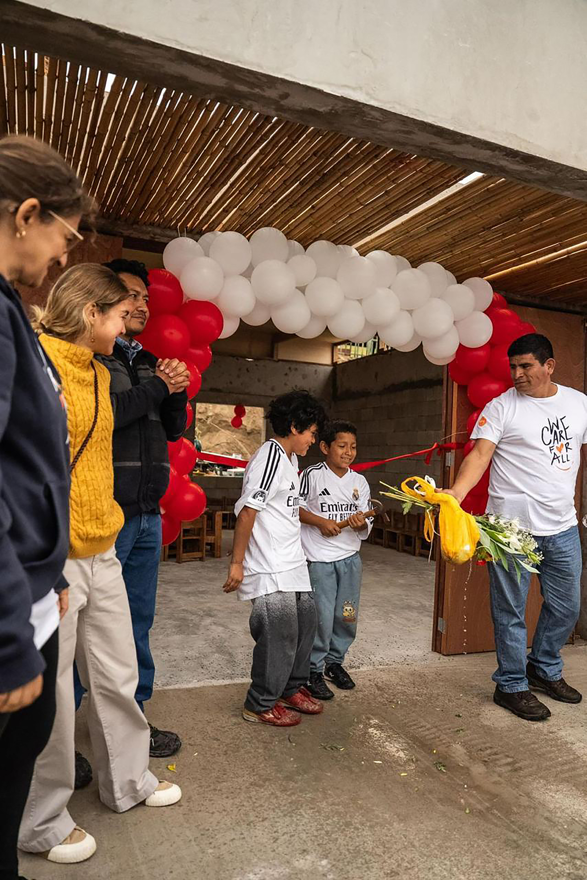 Opening ceremony with community members, red and white balloons, and children cutting a ribbon