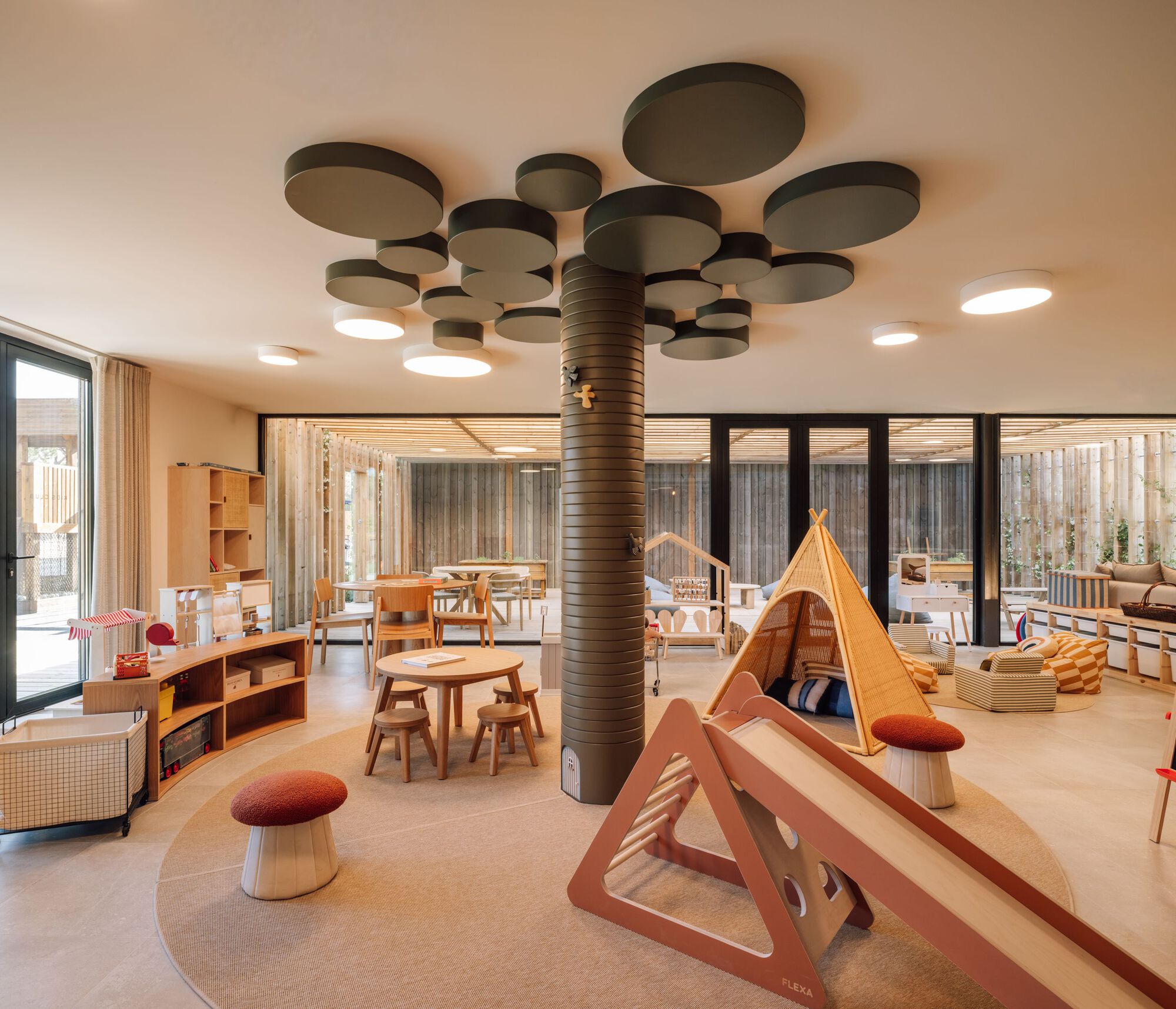 Play area with clustered circular ceiling panels, wrapped column and canvas tents on polished floor