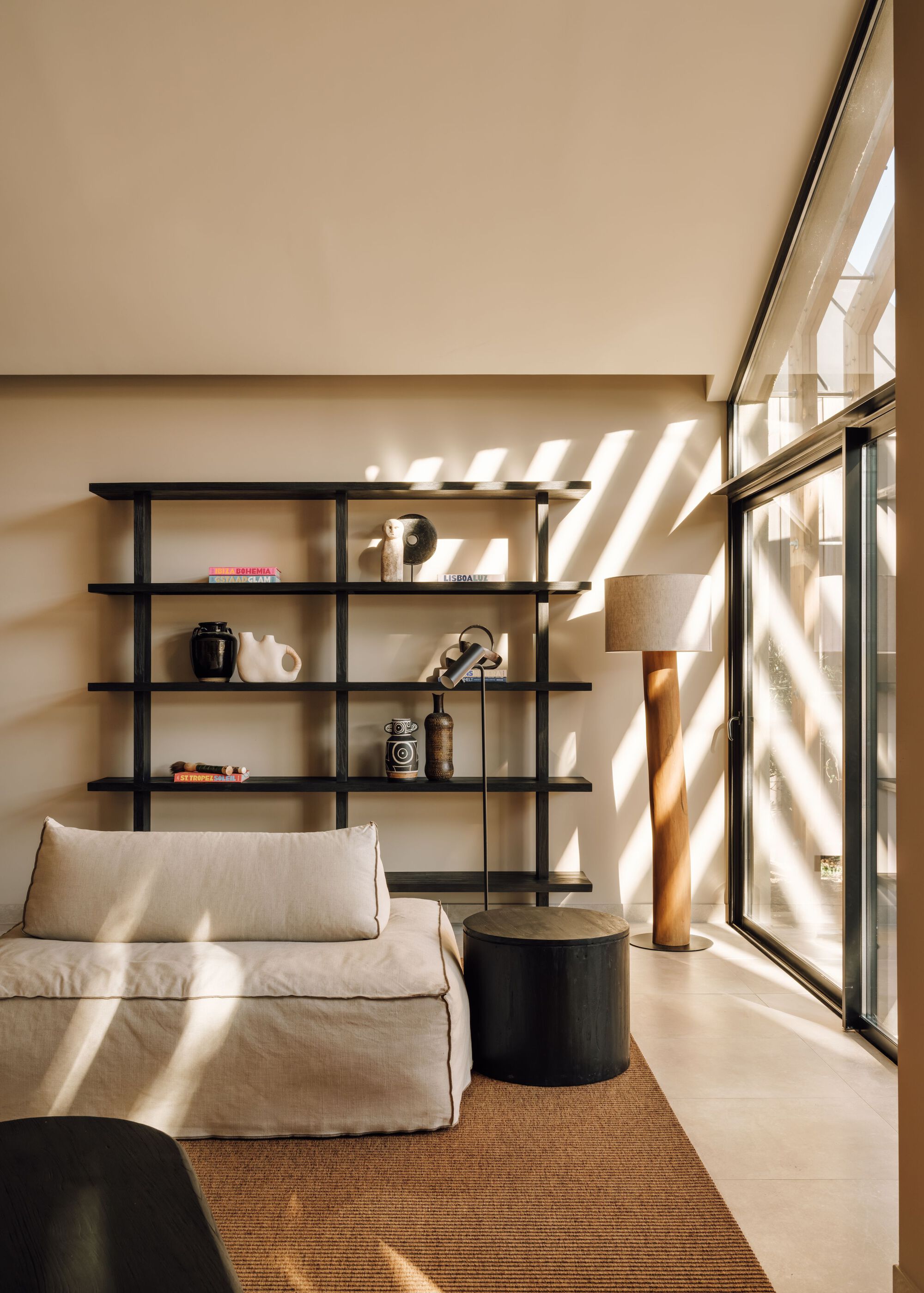 Reading nook with wall-mounted shelving casting diagonal shadows through glazed door at midday
