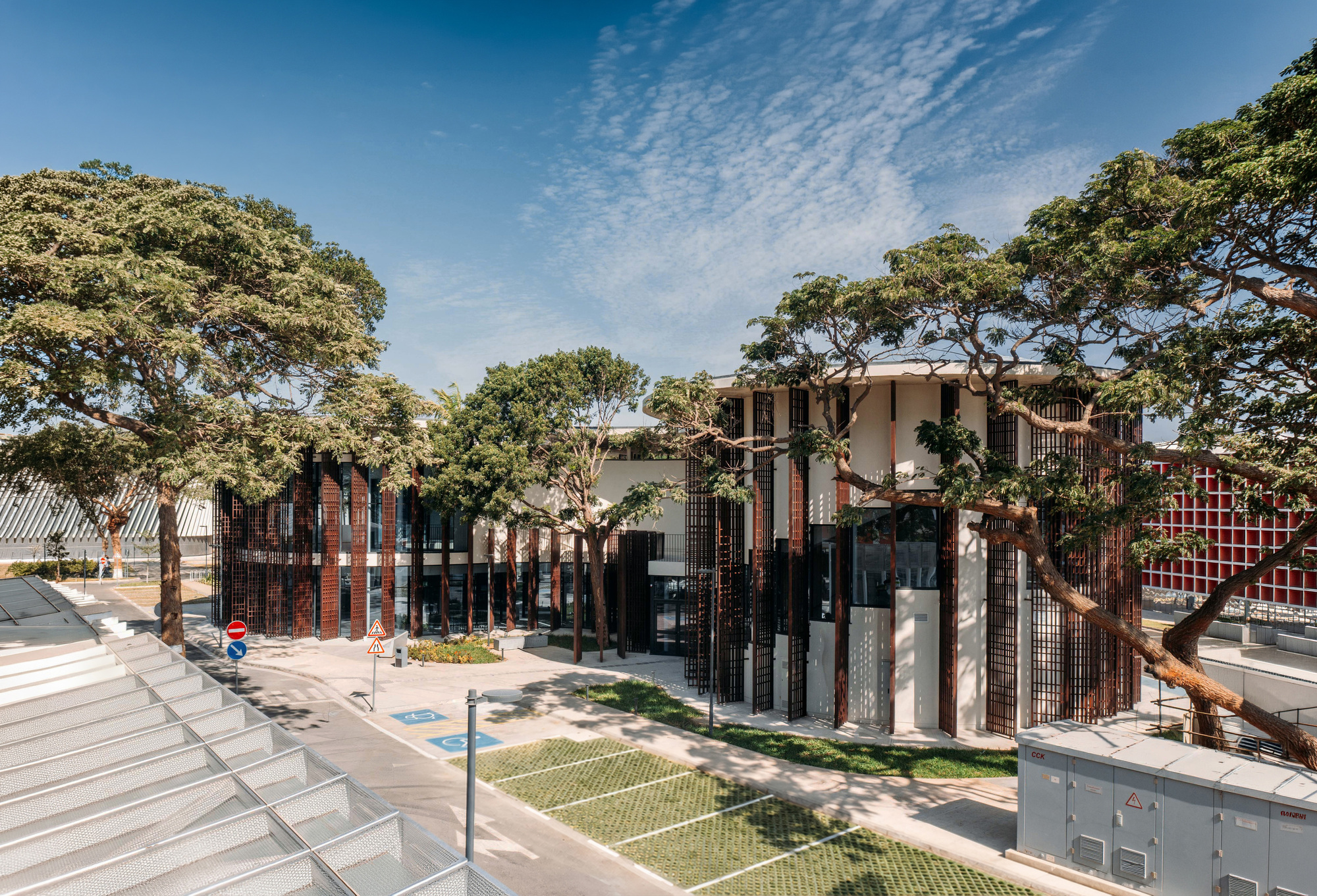 Terraced courtyard with vertical metal screens woven between preserved trees and planted beds