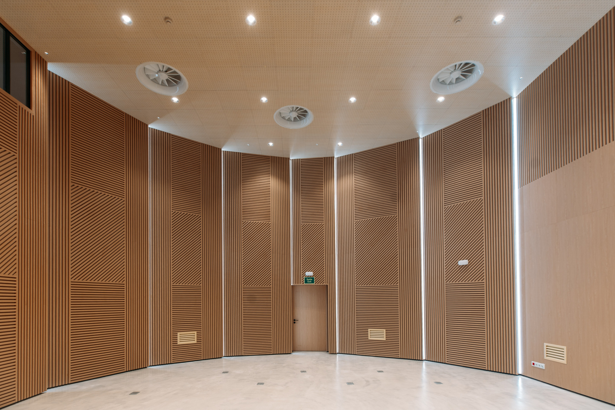 Curved interior hall with chevron-patterned timber wall panels and recessed ceiling lighting