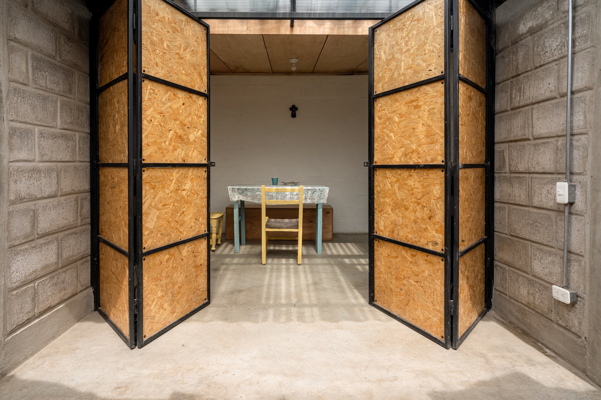 Bifold OSB panel doors with black steel frames opening onto a concrete floor dining area