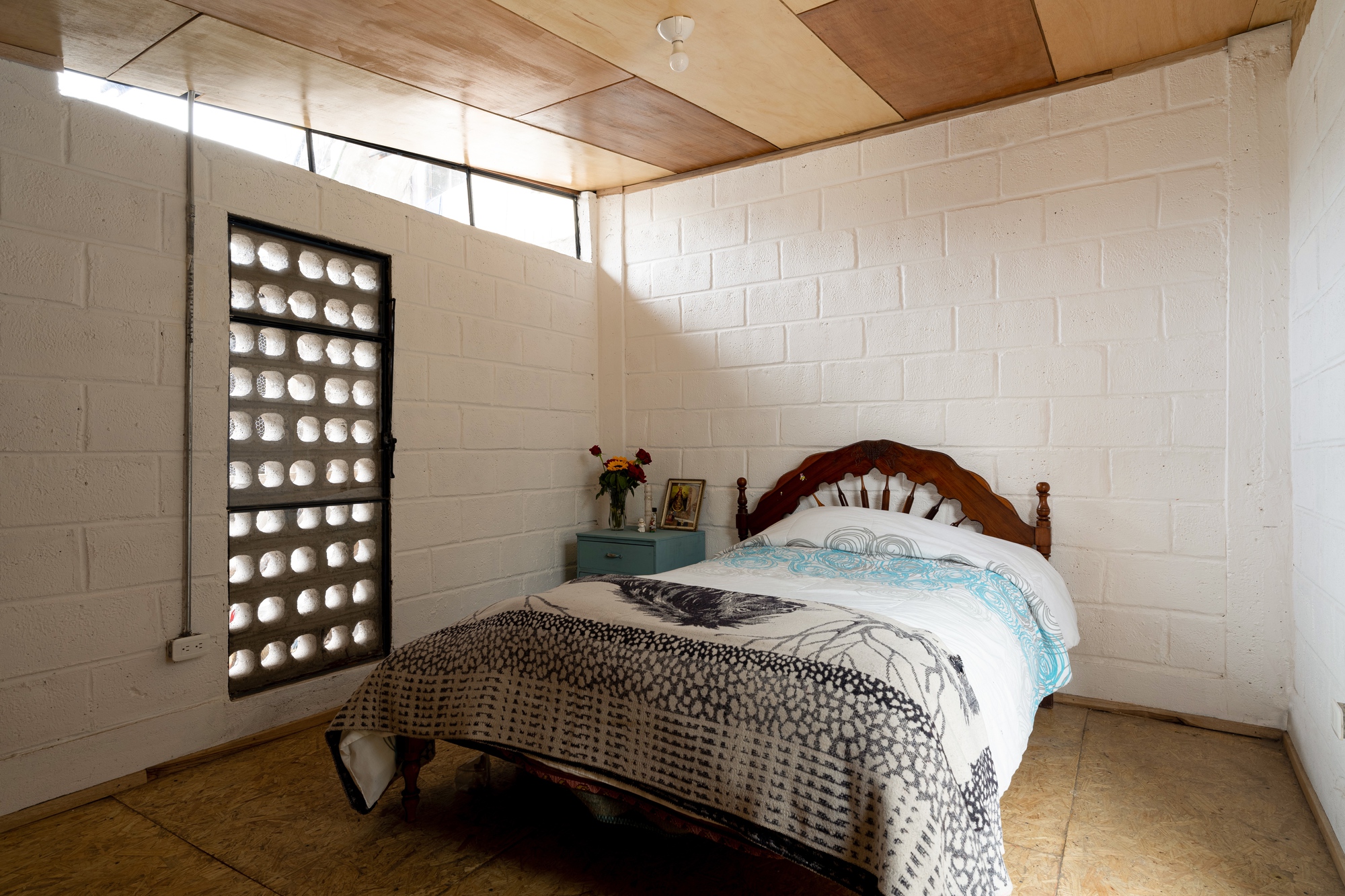 Bedroom corner with glass block window and clerestory skylight illuminating painted concrete block walls