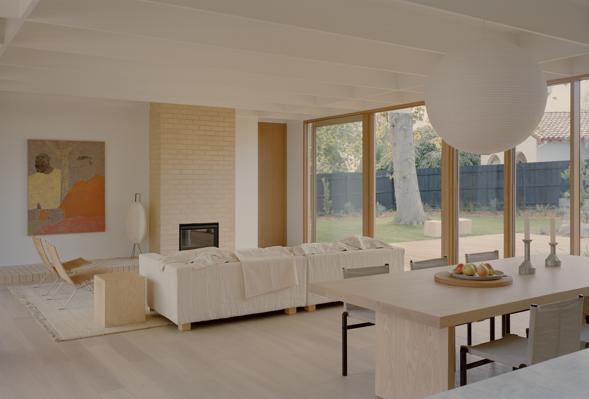 Living room with cream brick fireplace and full-height windows overlooking lawn and eucalyptus tree