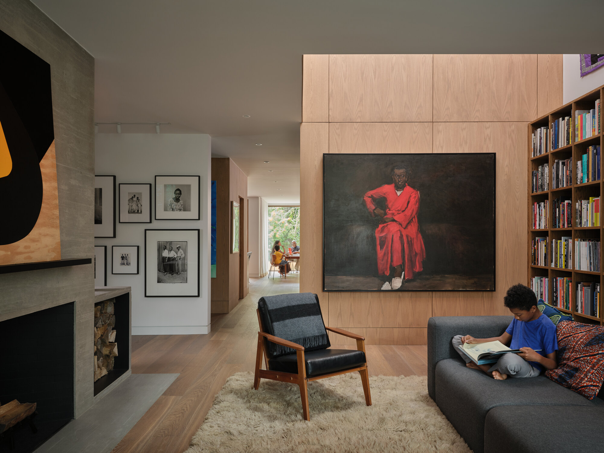 Living room with light wood cabinetry and built-in bookshelf, with a child reading on the sofa in afternoon light