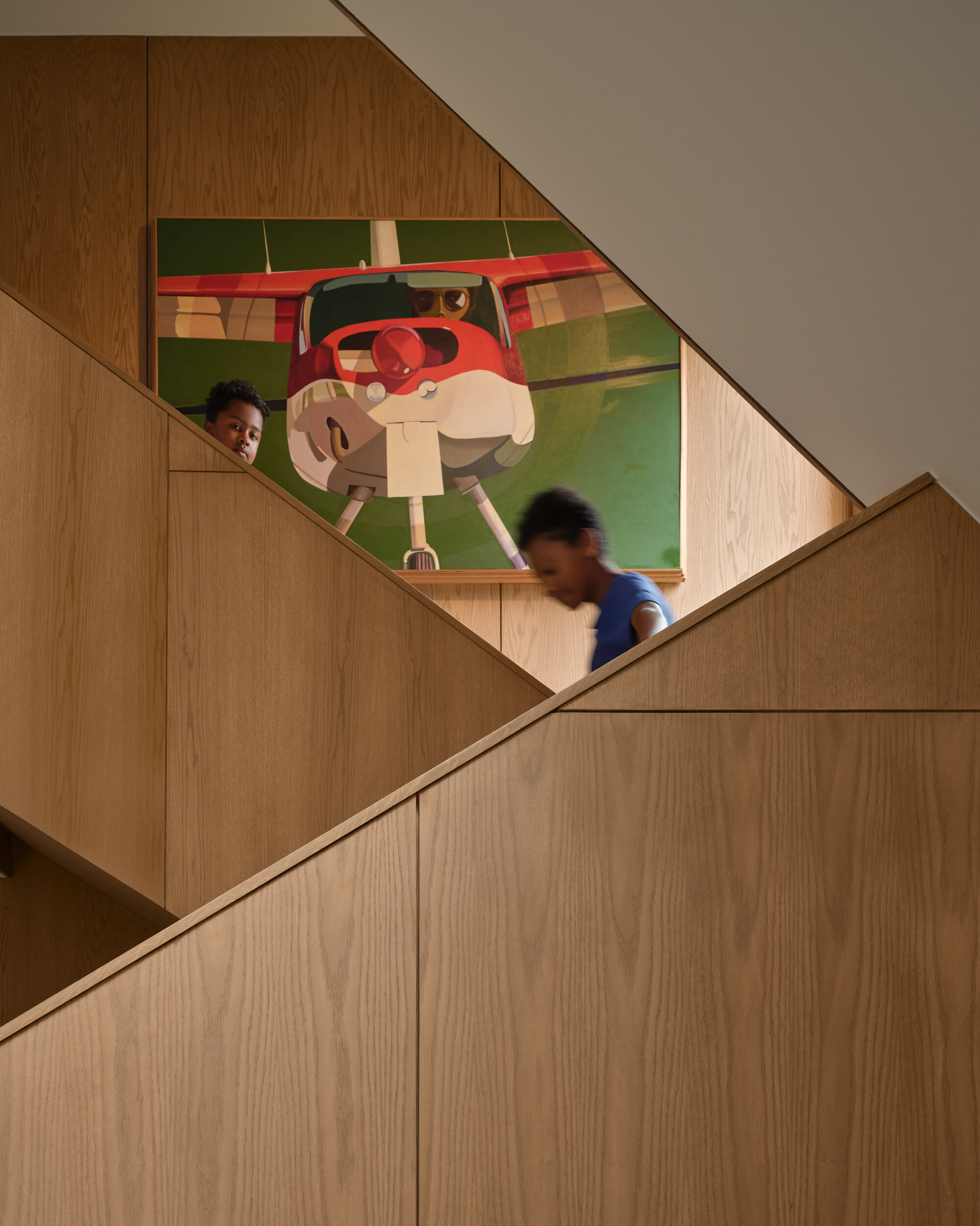 Wood staircase with two children ascending beneath a large figurative painting