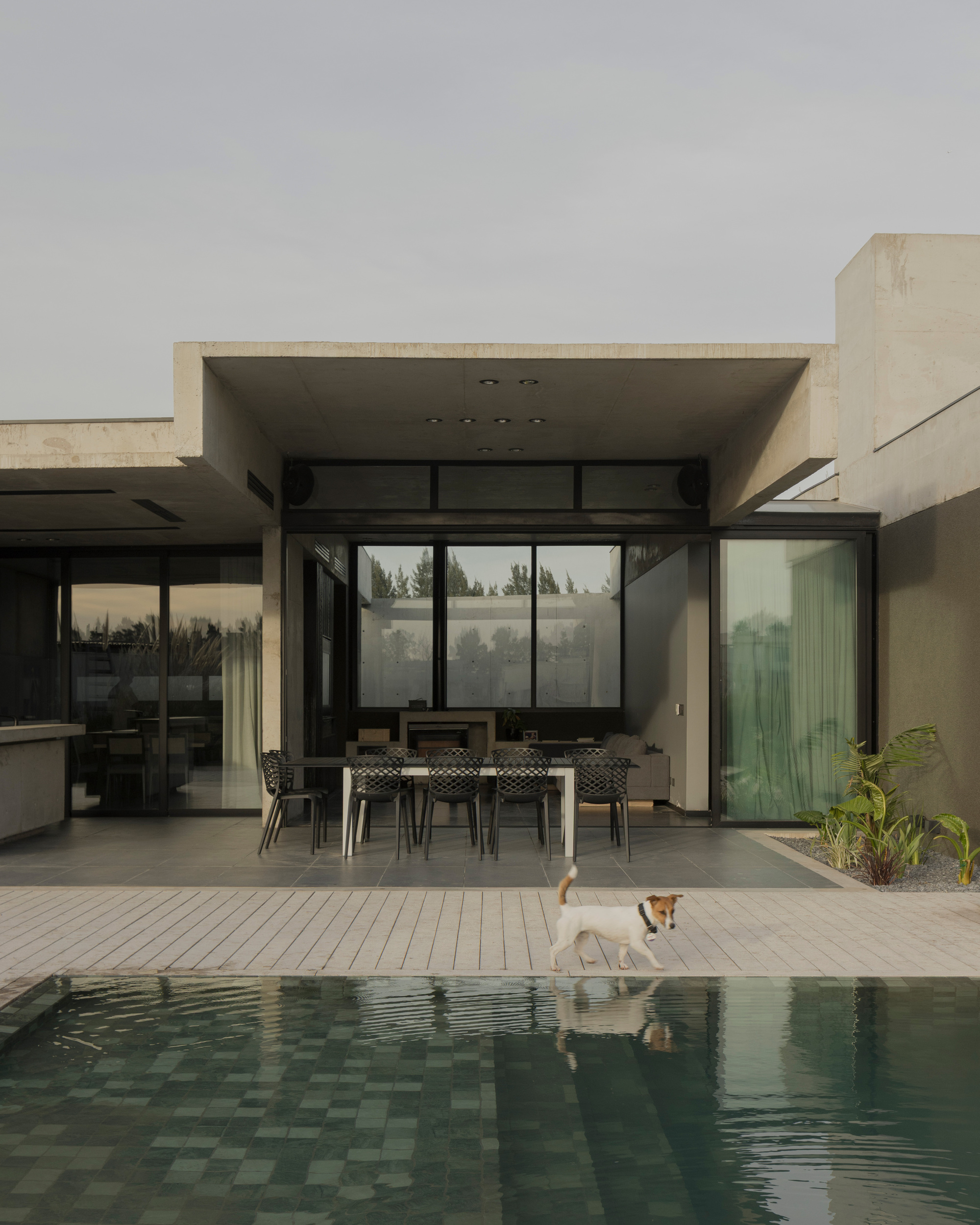 Covered terrace with timber decking, dining furniture and floor-to-ceiling glazing beside the pool