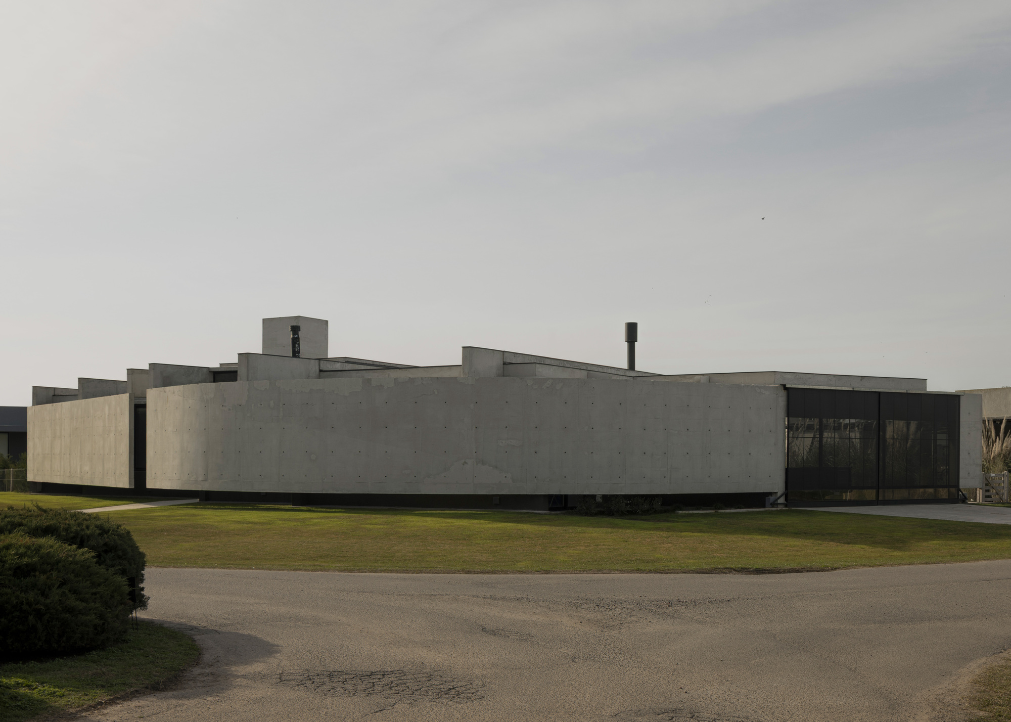 Curved concrete facade with stepped volumes and a central tower under an overcast sky