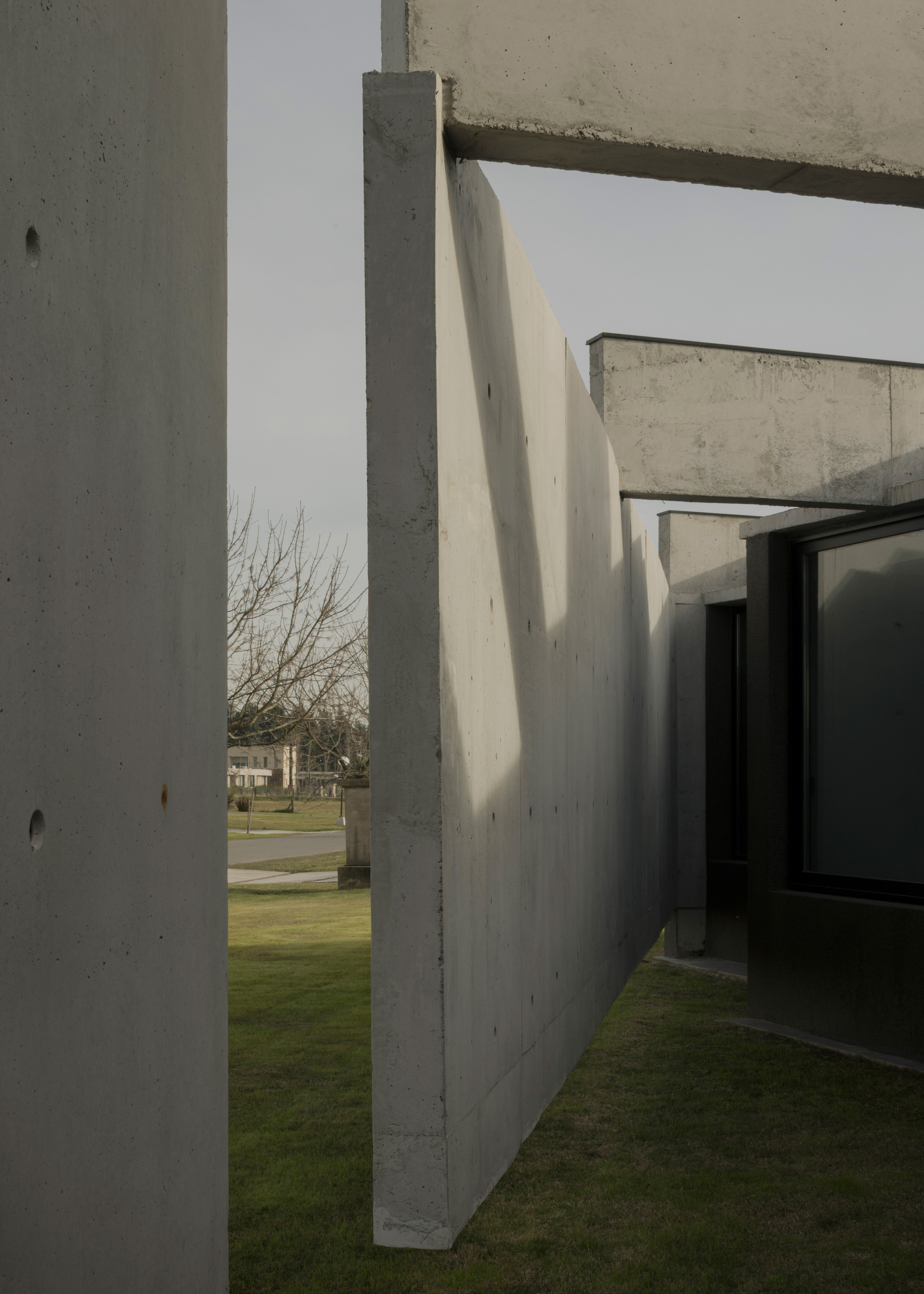 Vertical slot between concrete walls framing a view of winter trees and lawn beyond