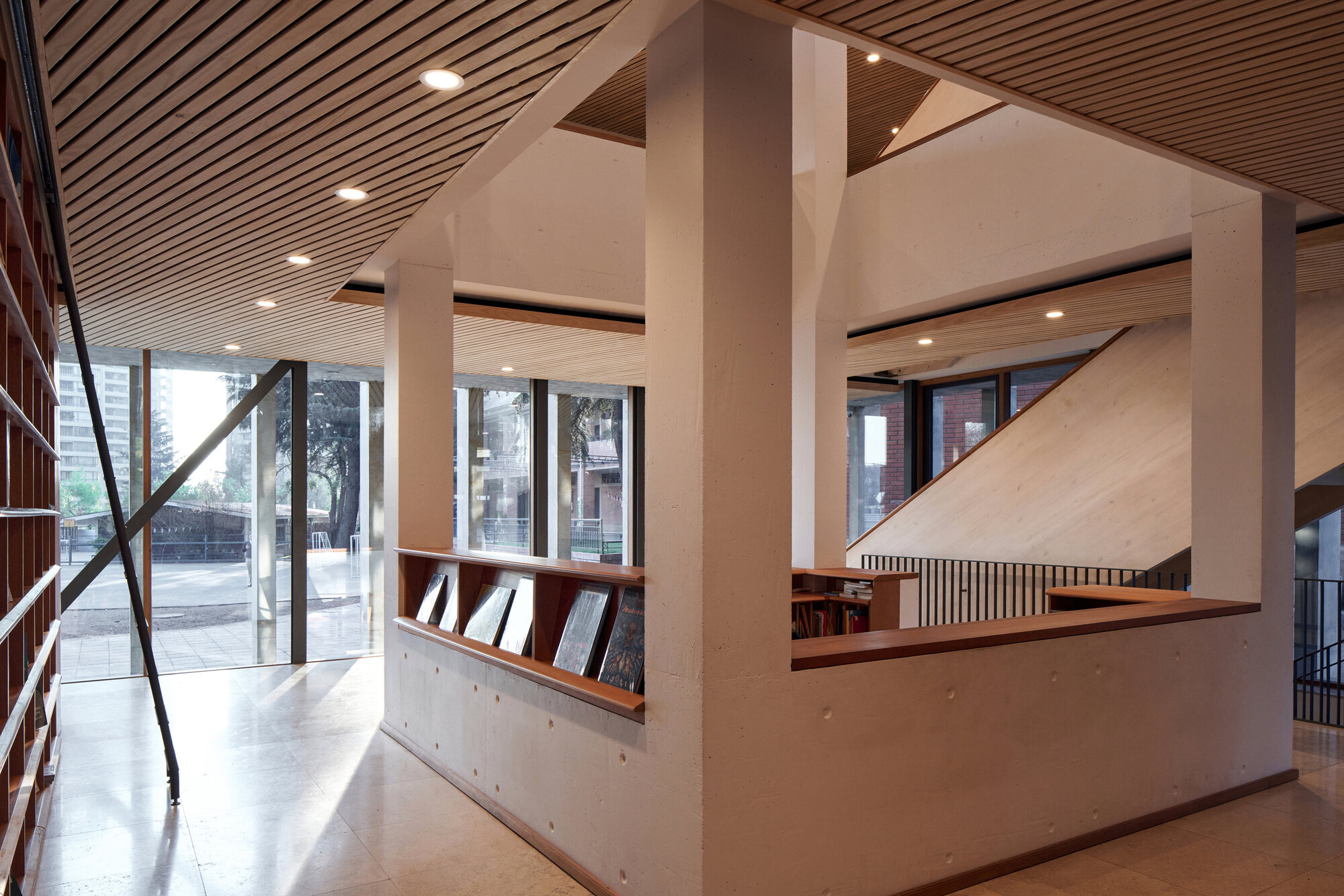 Library interior showing plywood balustrade, white concrete columns and diagonal steel bracing at the glazed facade