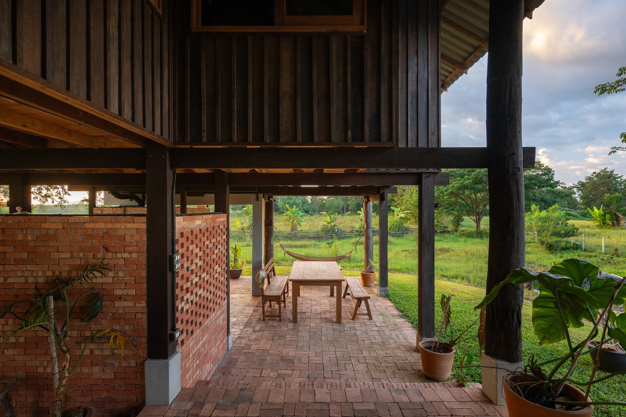 Outdoor terrace with brick pavers and dining table between perforated brick screen and potted plants