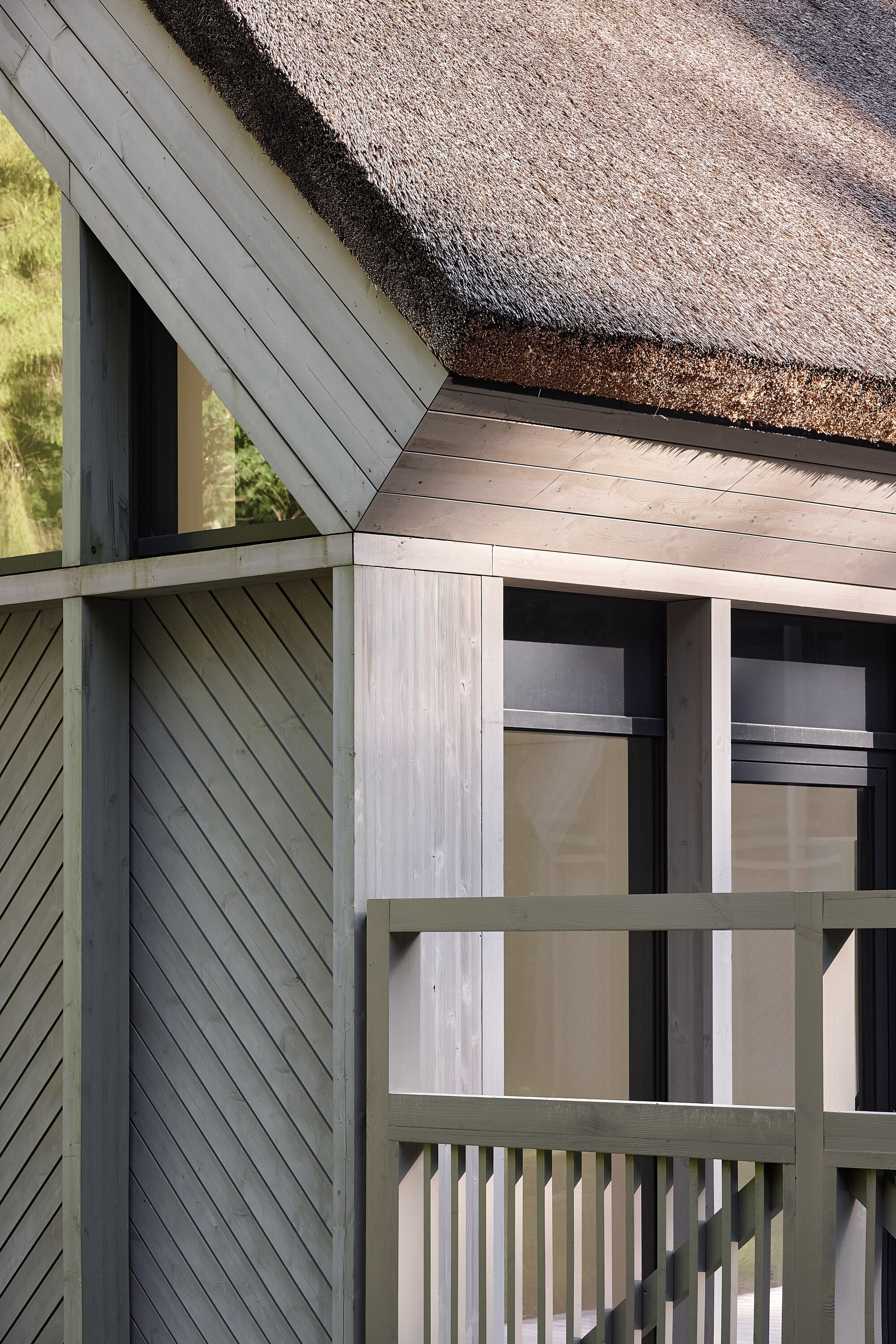 Detail of diagonal timber cladding meeting thatched roof edge and white timber balustrade