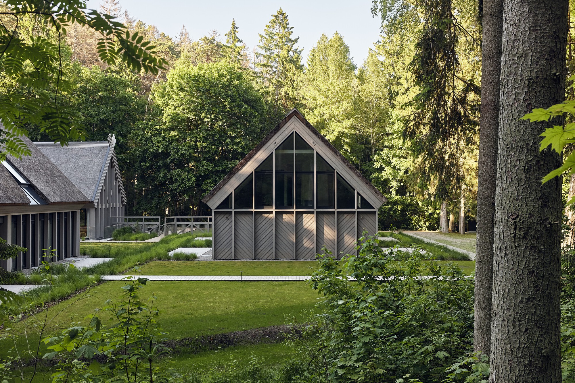 Central pavilion with diagonal lattice gable and horizontal cladding surrounded by planted grasses