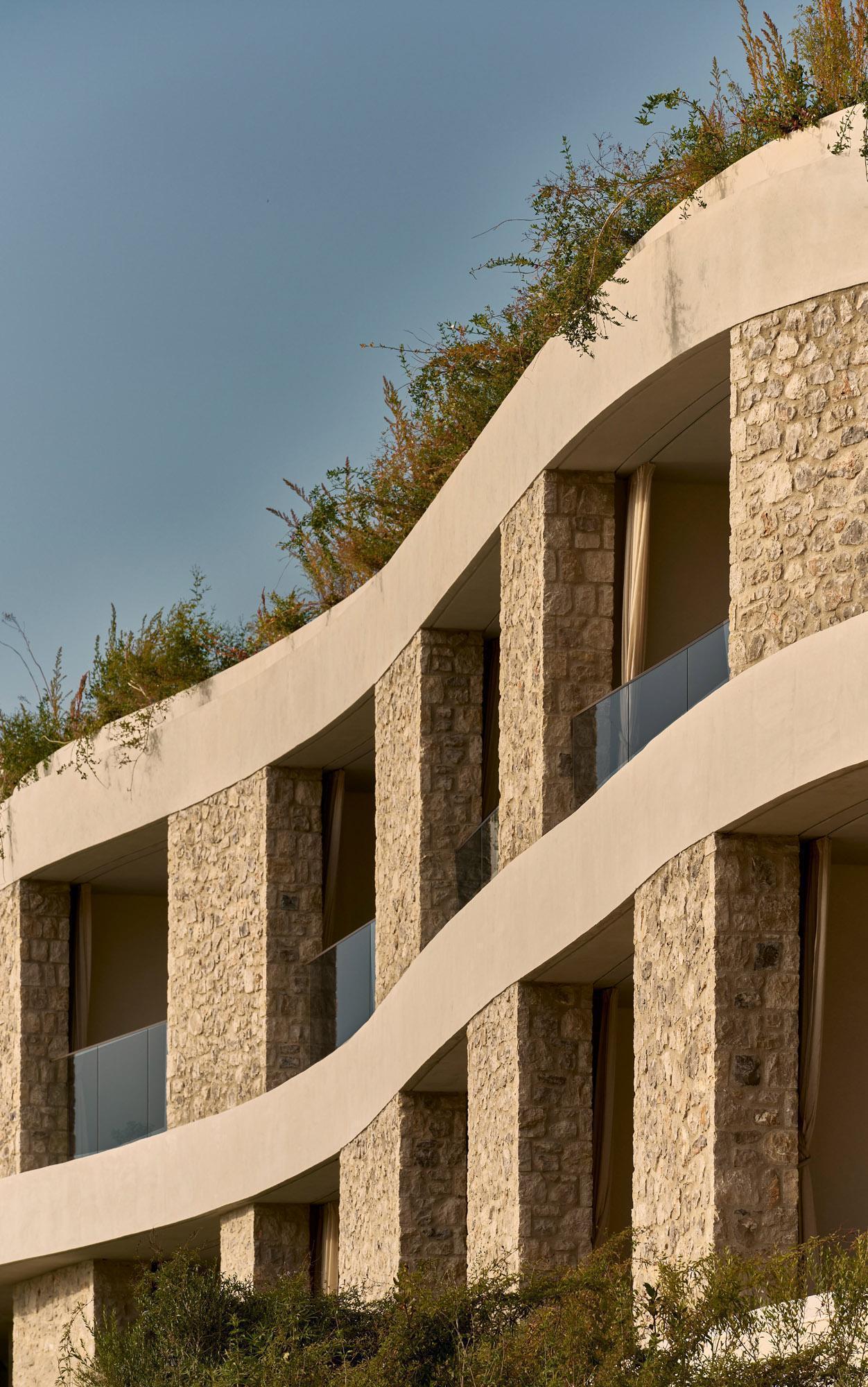Stacked balconies with stone piers and white concrete bands under late afternoon sunlight