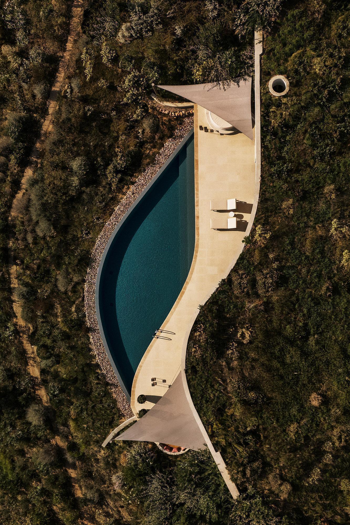 Aerial view of the curved pool terrace surrounded by scrubland and scattered trees