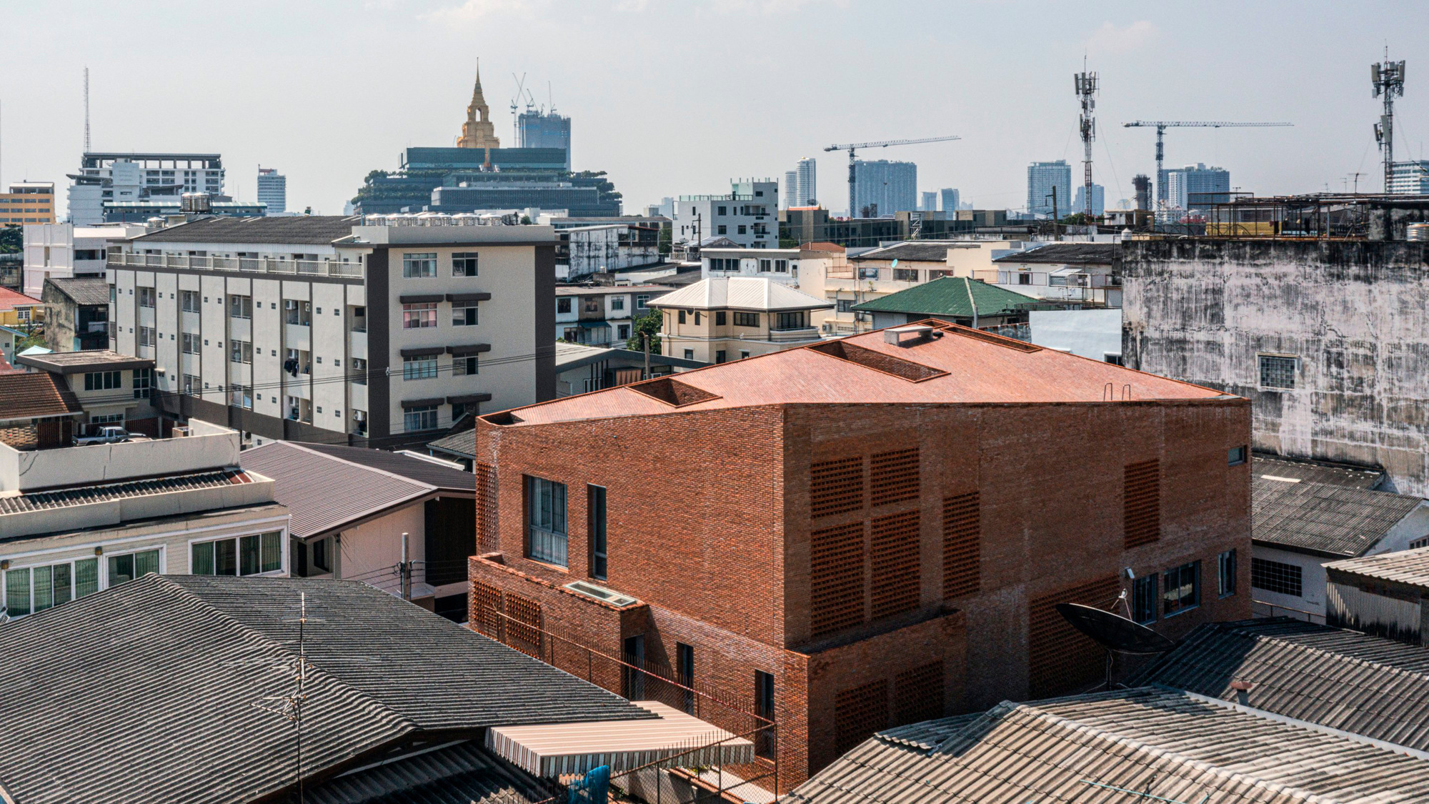 Aerial view of the brick building with perforated walls among surrounding low-rise urban structures