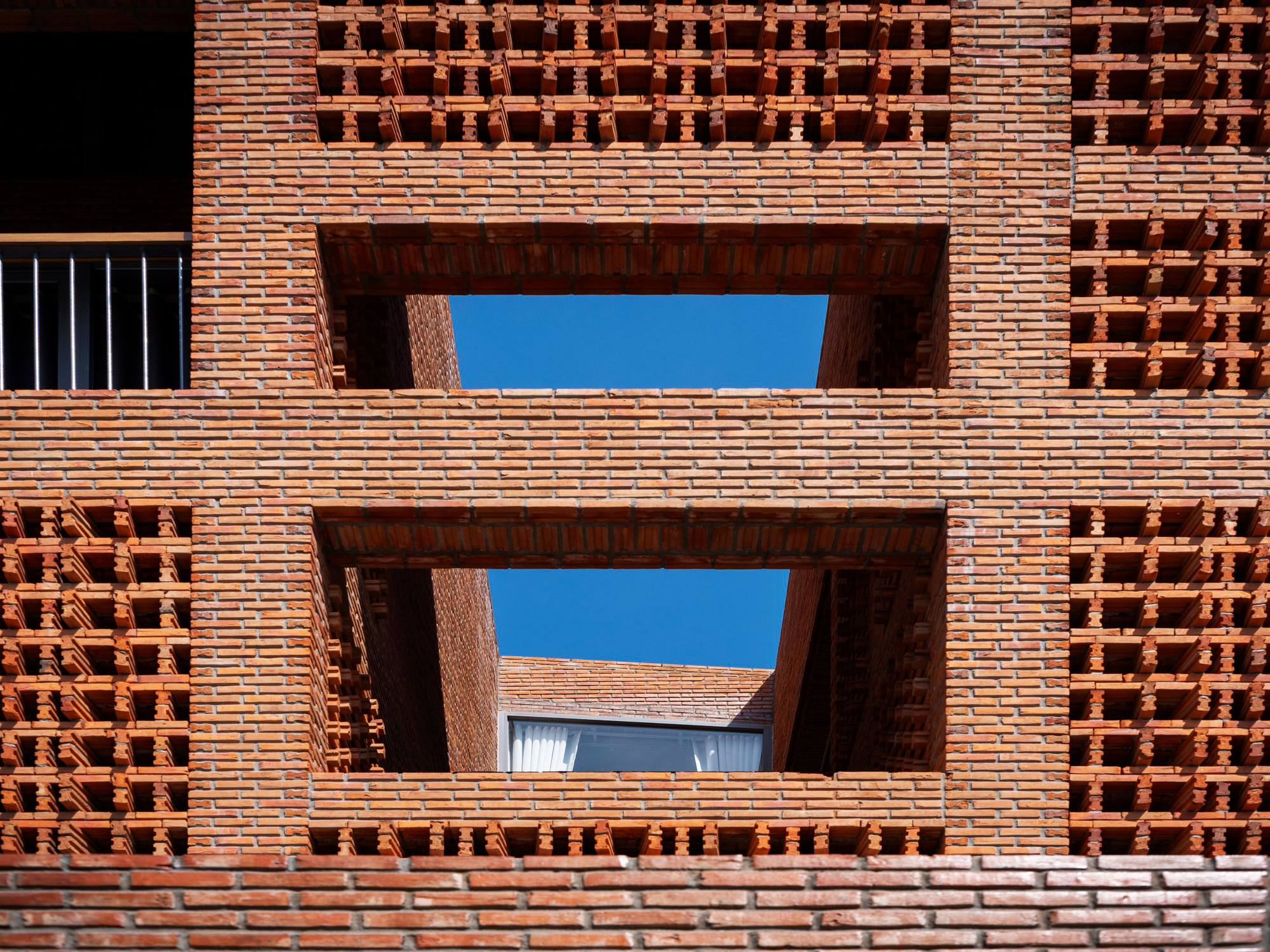 Upward view through stacked brick balconies framing blue sky above