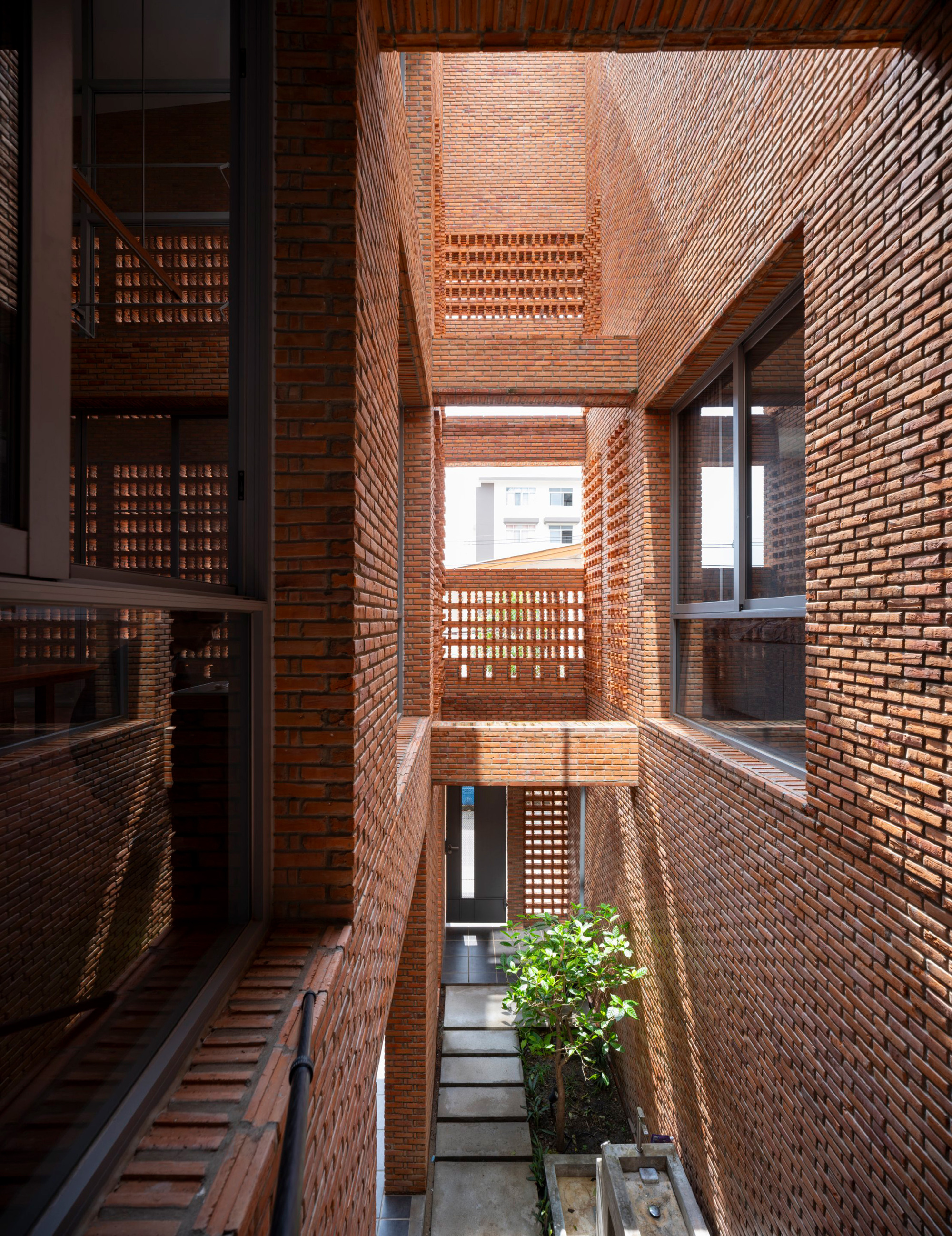 Interior courtyard with perforated brick walls rising three stories around a planted bed below