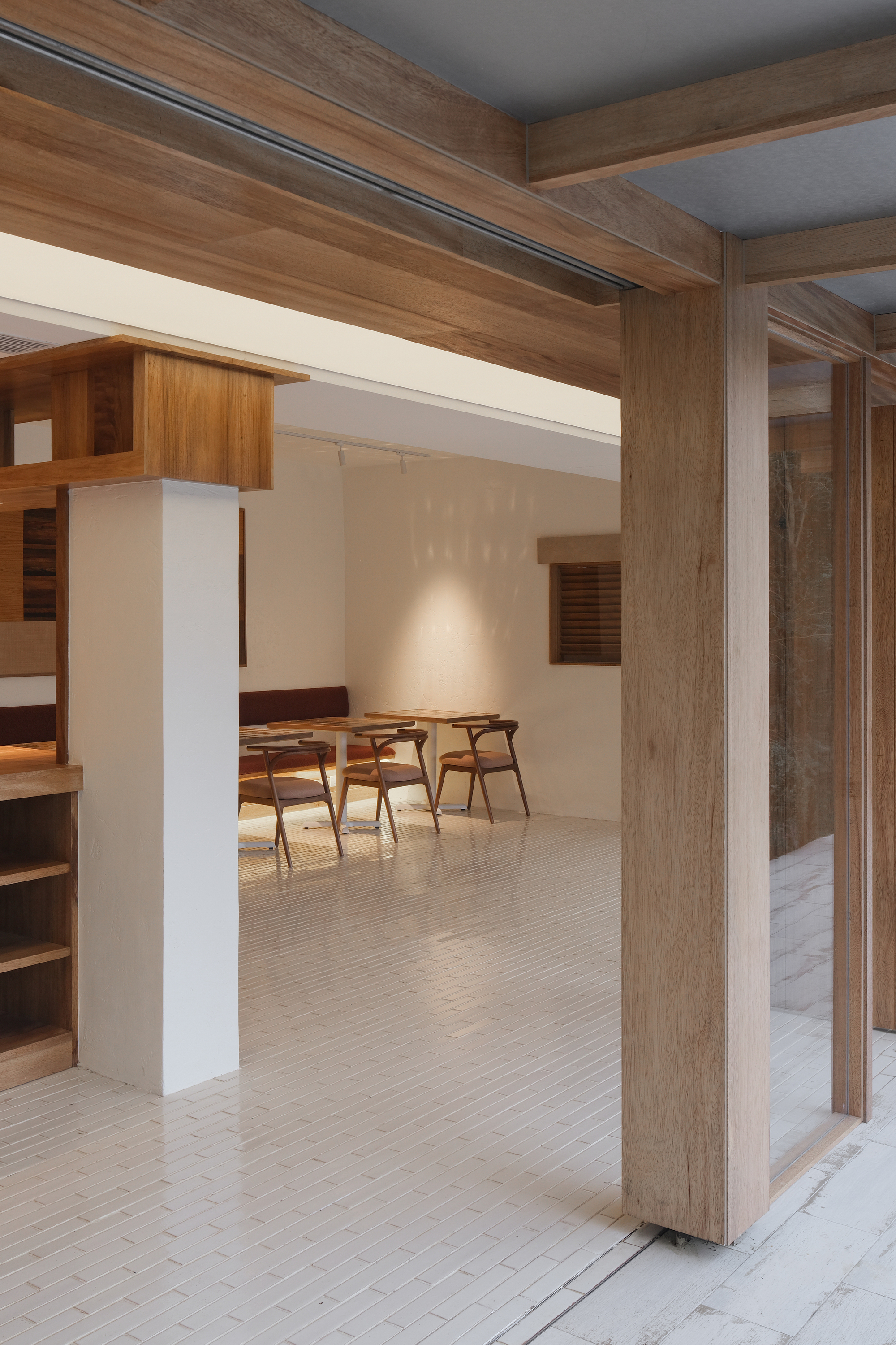 Interior view through timber portal frame into dining area with exposed ceiling beams