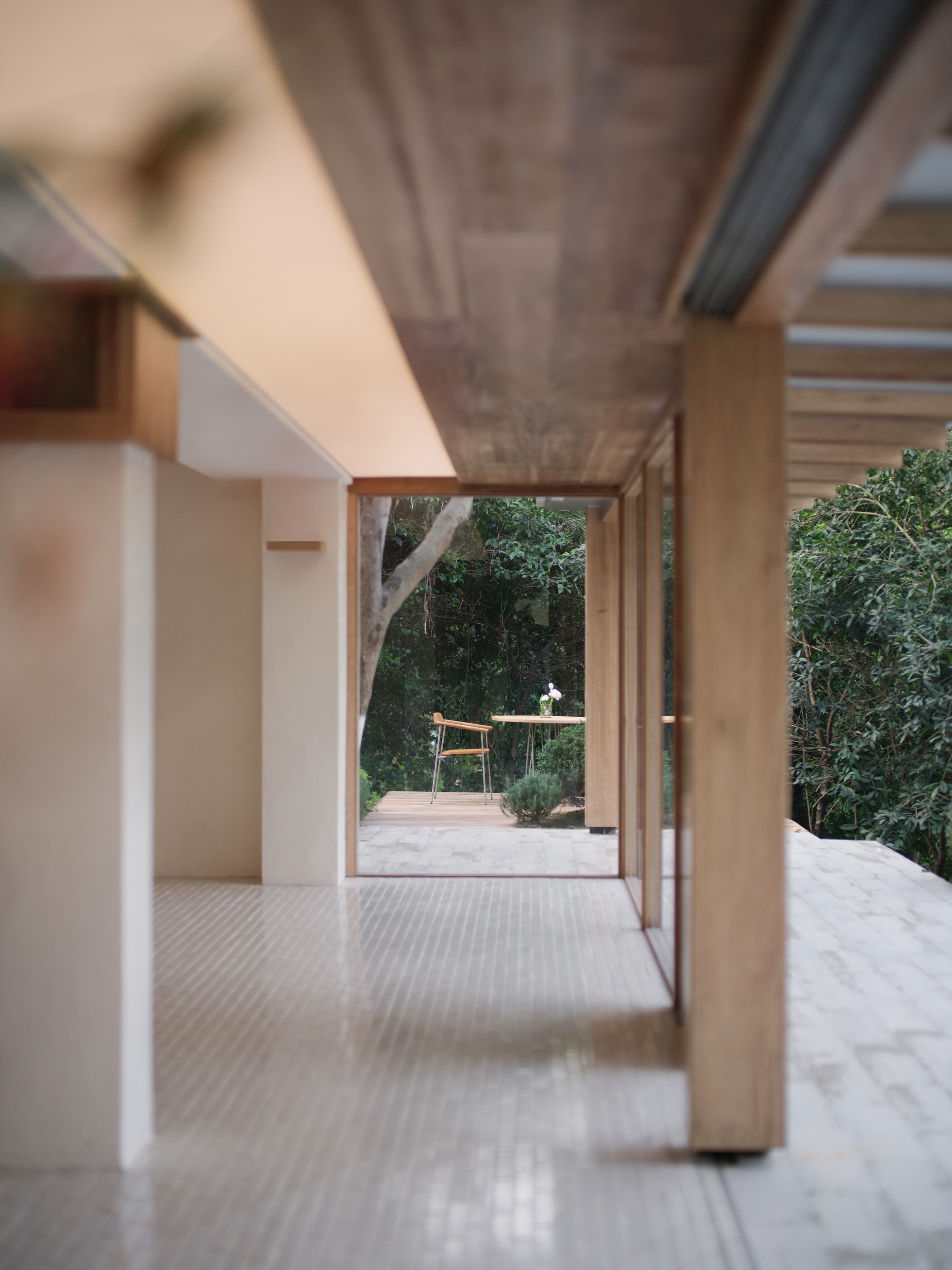 Interior corridor with exposed concrete ceiling and timber sliding doors opening to a garden terrace
